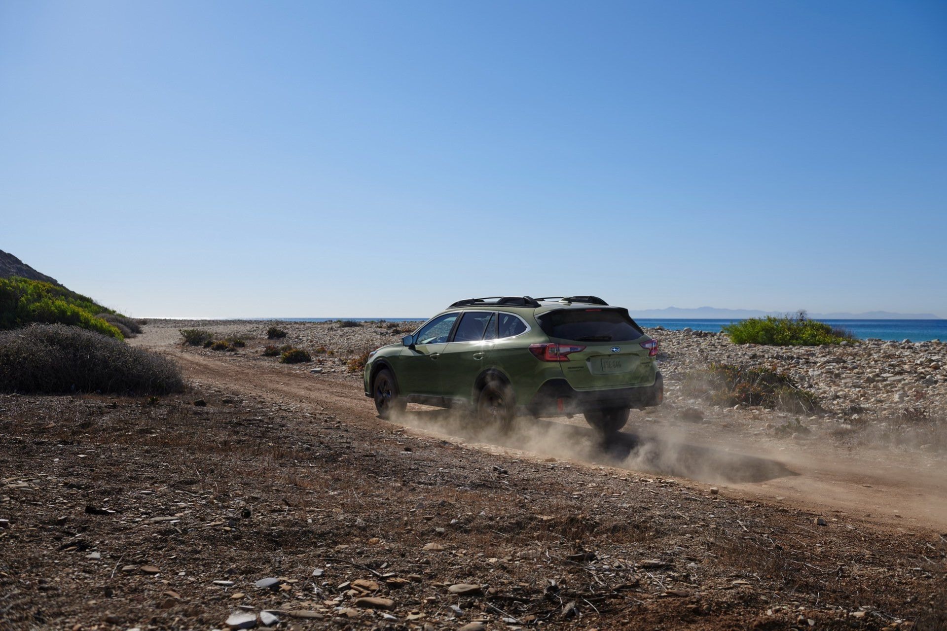 El Subaru Outback levantando polvo en un camino costero, mostrando su espíritu aventurero.