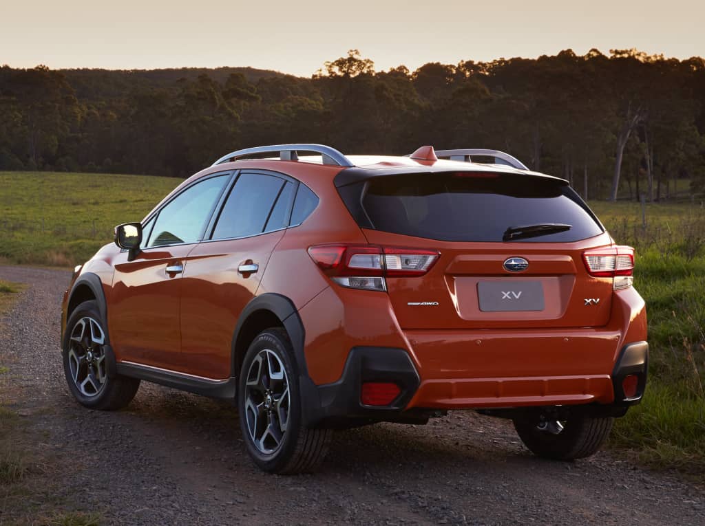Vista trasera lateral del Subaru XV en color naranja en un entorno natural.