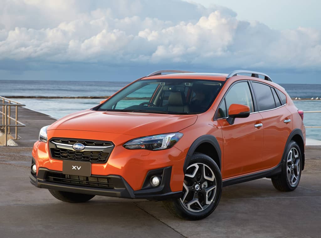 Subaru XV en color naranja, vista lateral delantera junto al mar.