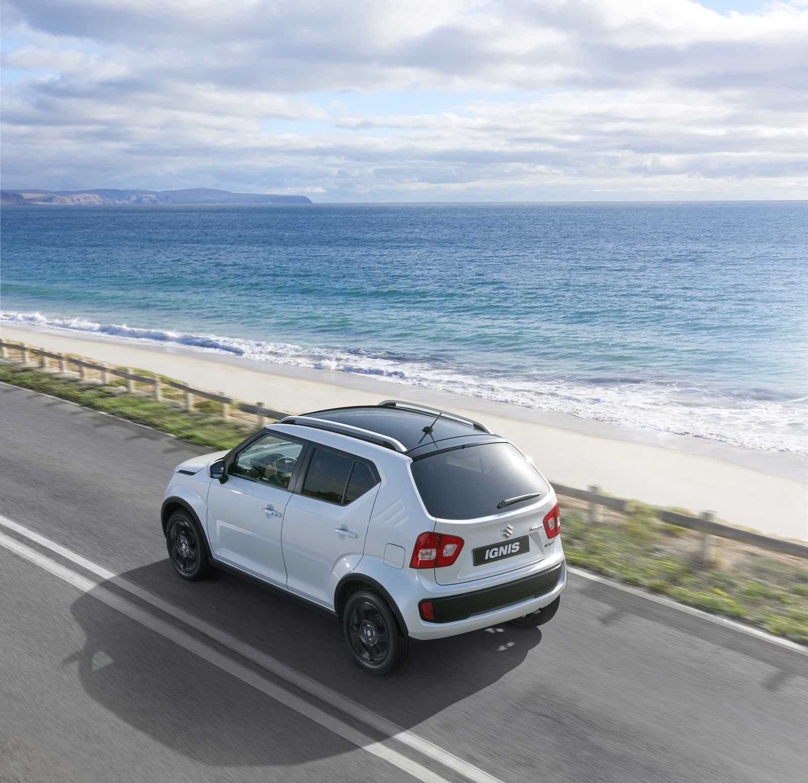 Perfil lateral del Suzuki Ignis en movimiento por carretera costera.