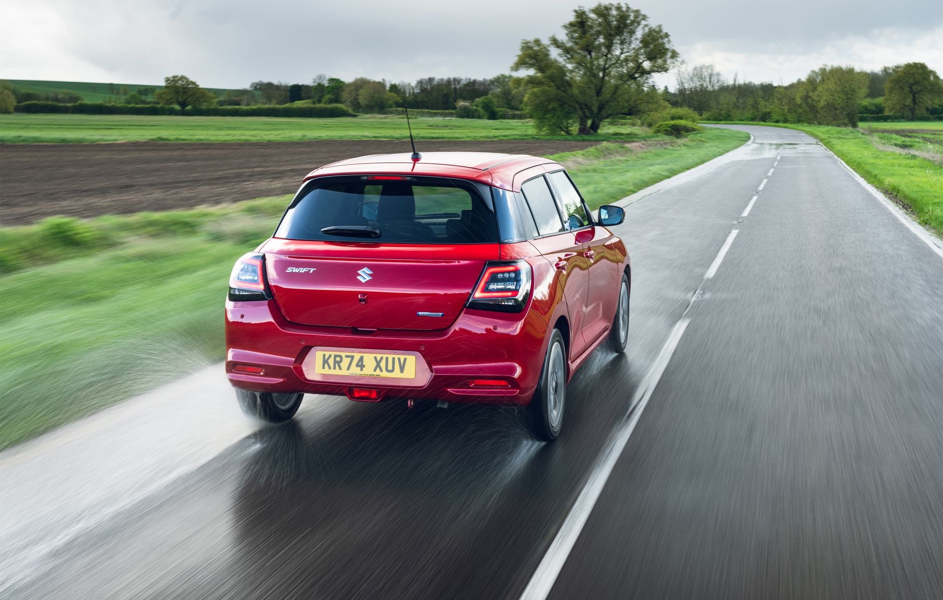 El Suzuki Swift navega por un paisaje rural, destacando su versatilidad.