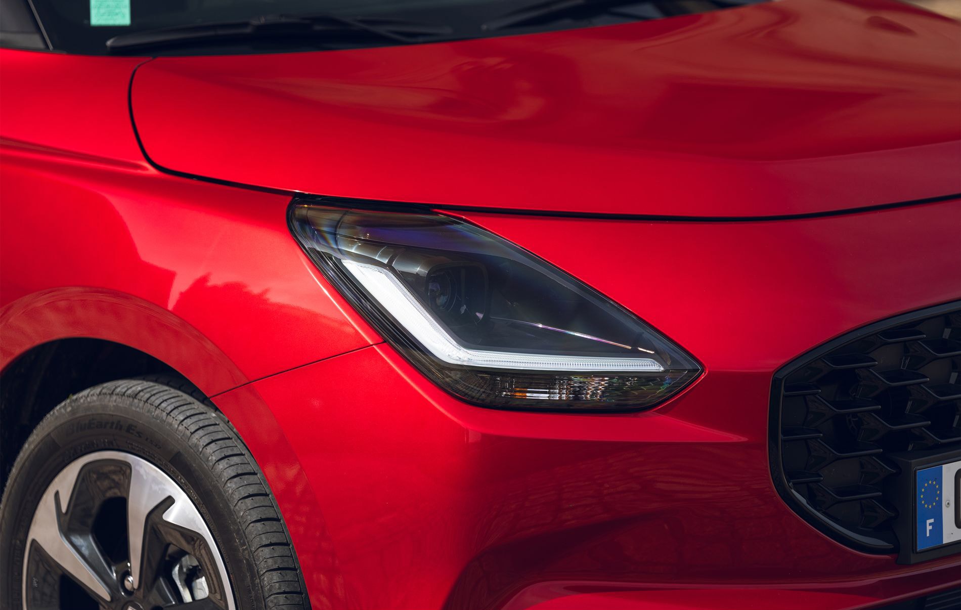 Vista frontal del Suzuki Swift rojo, destacando su parrilla distintiva y estilo.