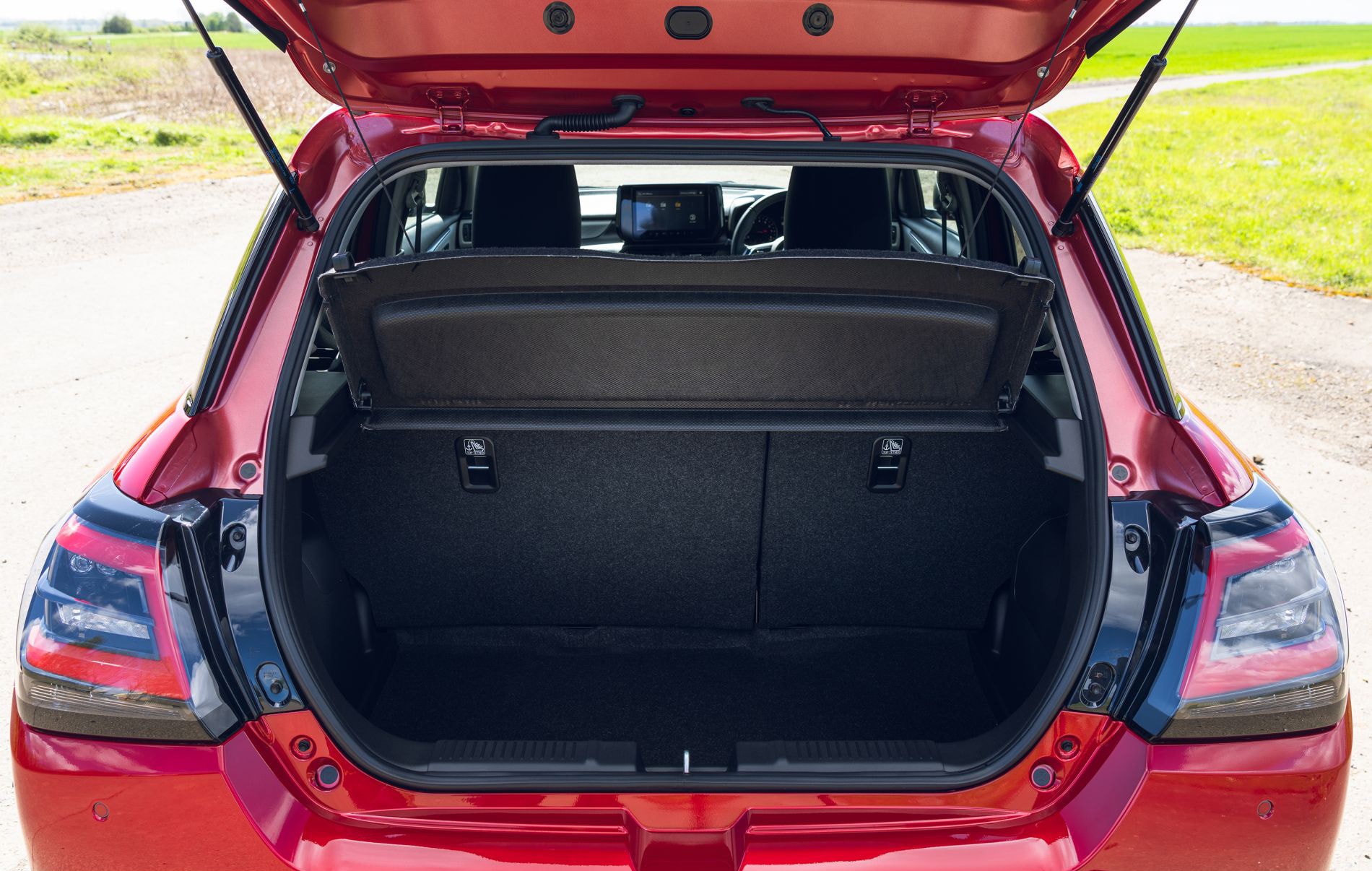 Vista trasera del Suzuki Swift azul frente a una espectacular casa.