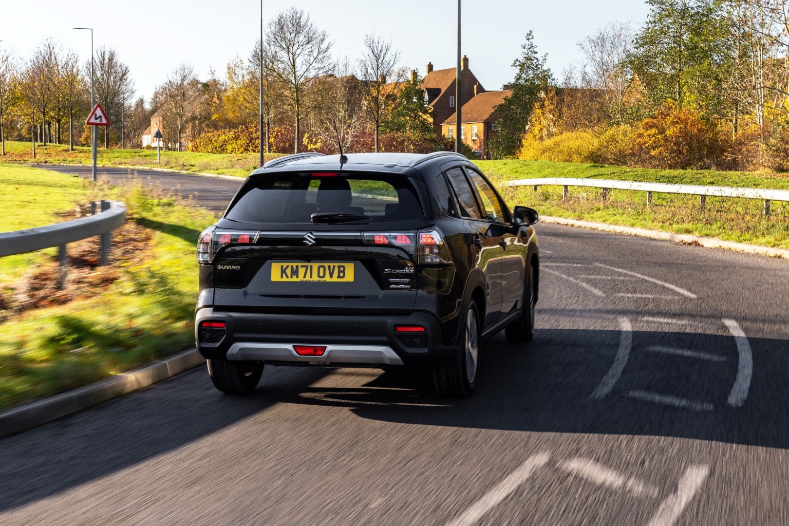 S-Cross híbrido capturado en movimiento desde una perspectiva trasera-lateral.