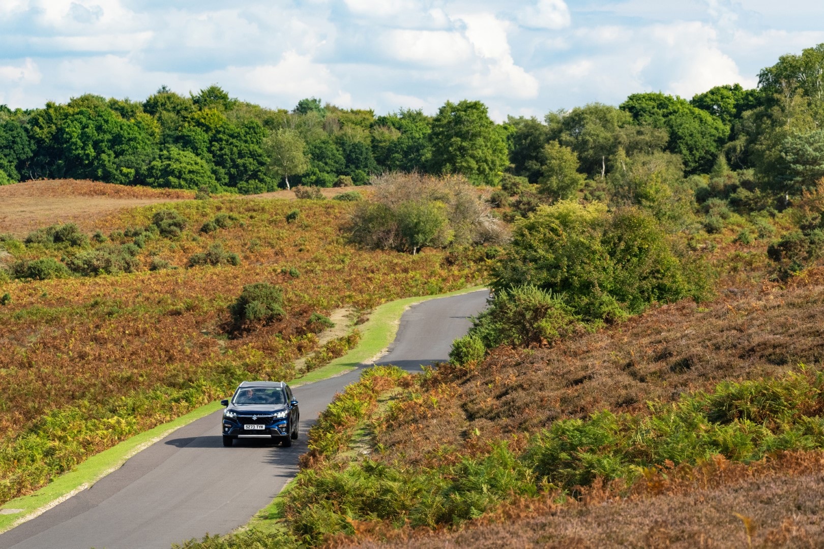 Vista lateral del Suzuki S-Cross híbrido en un entorno natural, demostrando su capacidad en carretera