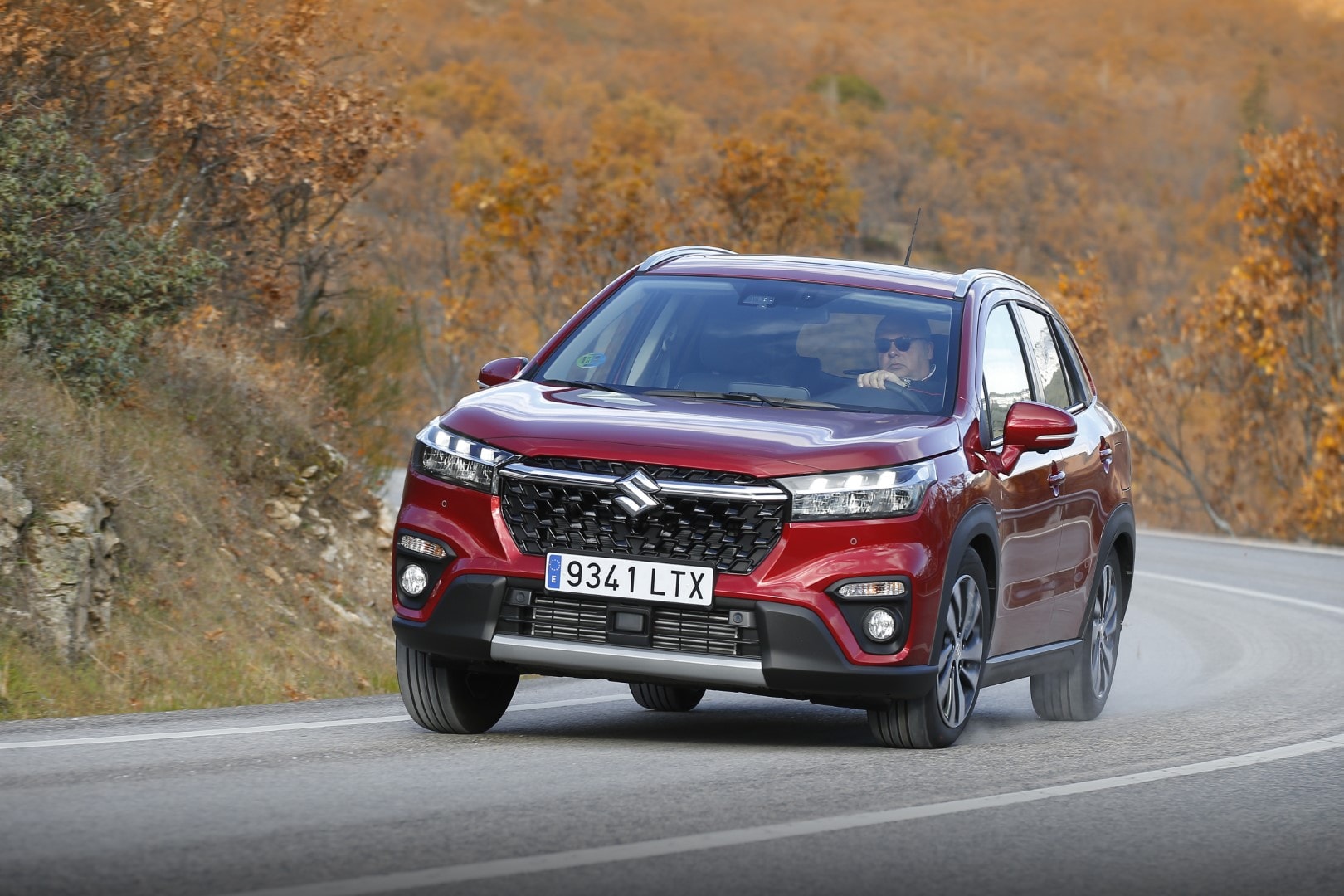 Imagen del Suzuki S-Cross en movimiento por una carretera otoñal.