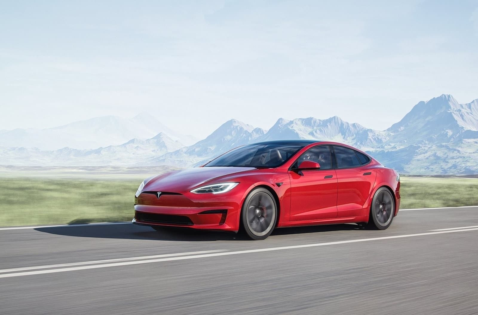 Tesla Model S rojo con la elegancia característica de su diseño transitando por un entorno natural.