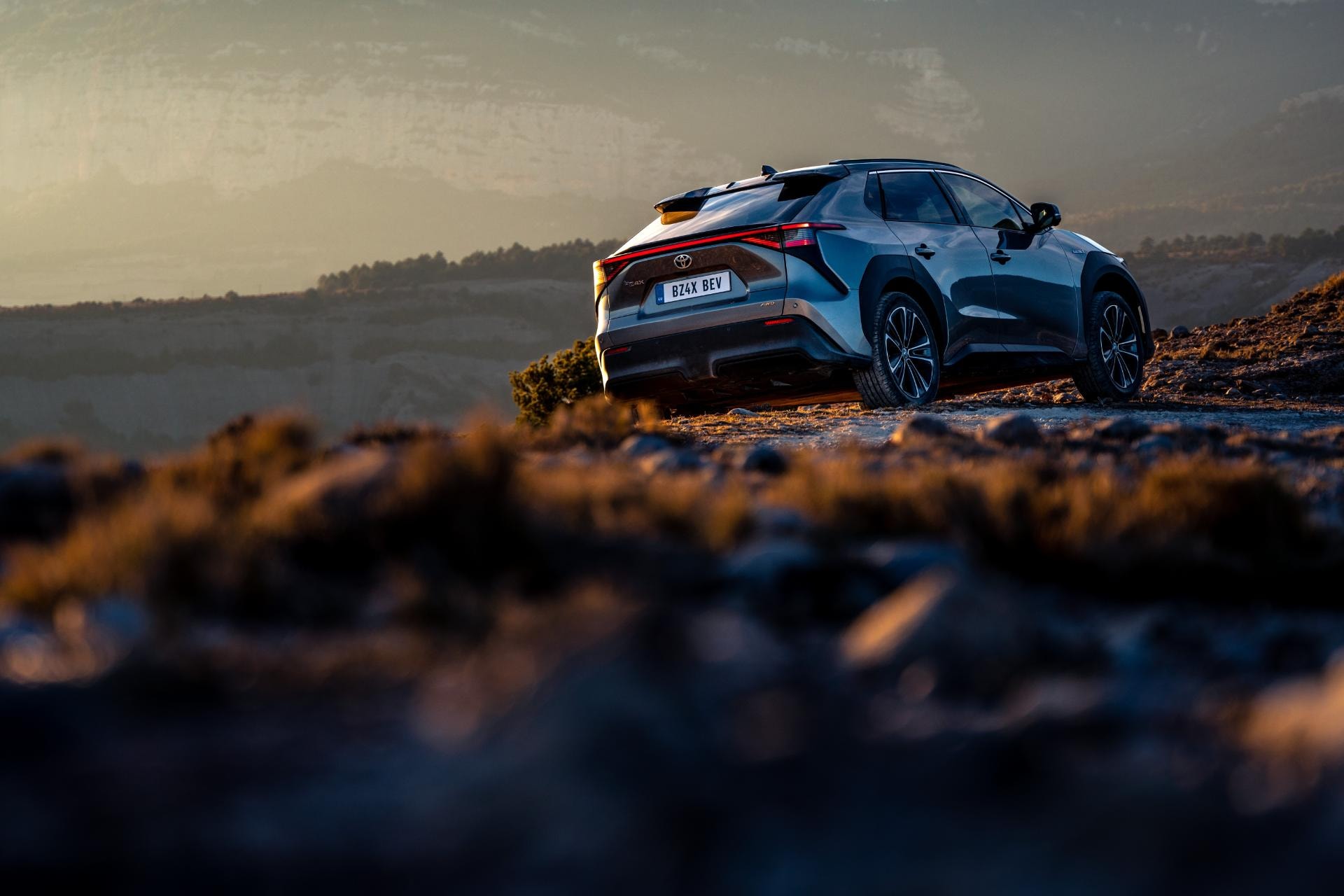Vista trasera y lateral del Toyota bZ4X en un paisaje al atardecer.