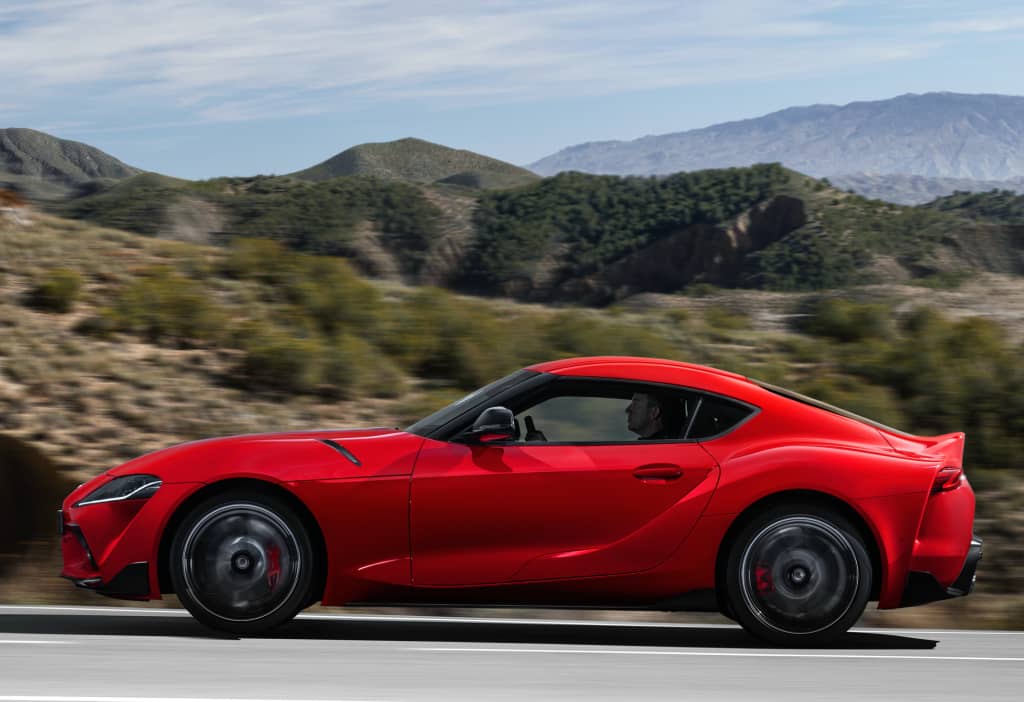 Visión lateral dinámica del Toyota GR Supra recorriendo una carretera.