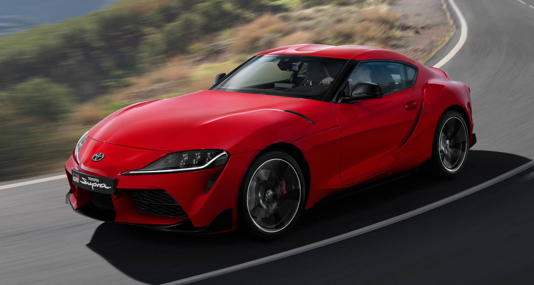 El Toyota GR Supra rojo en acción, destacando su perfil ágil y deportivo.