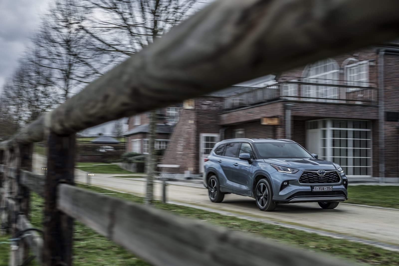 Toyota Highlander Híbrido aproximándose con estilo por un camino urbano.