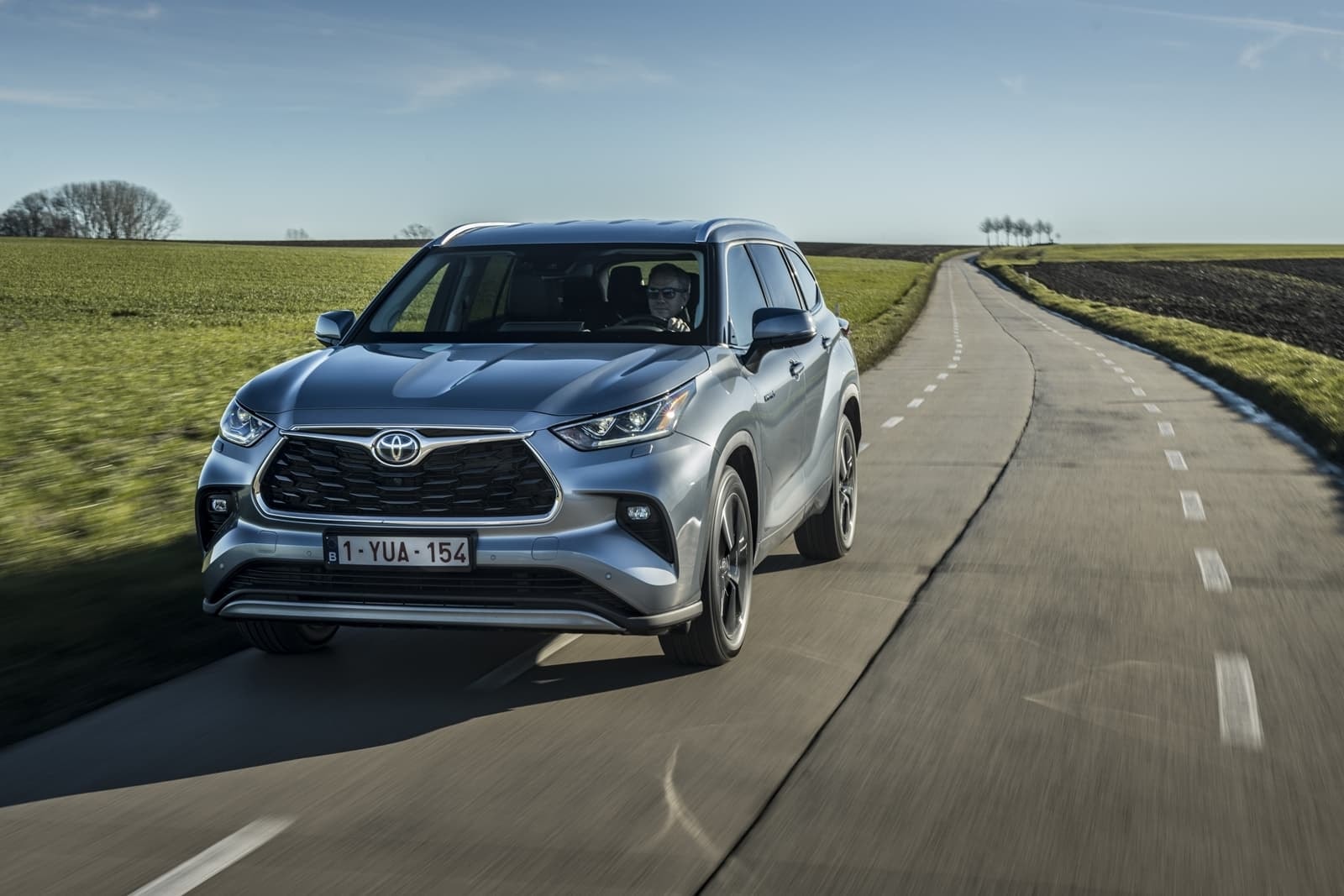 Vista frontal y lateral del Toyota Highlander Híbrido en una carretera con curvas.