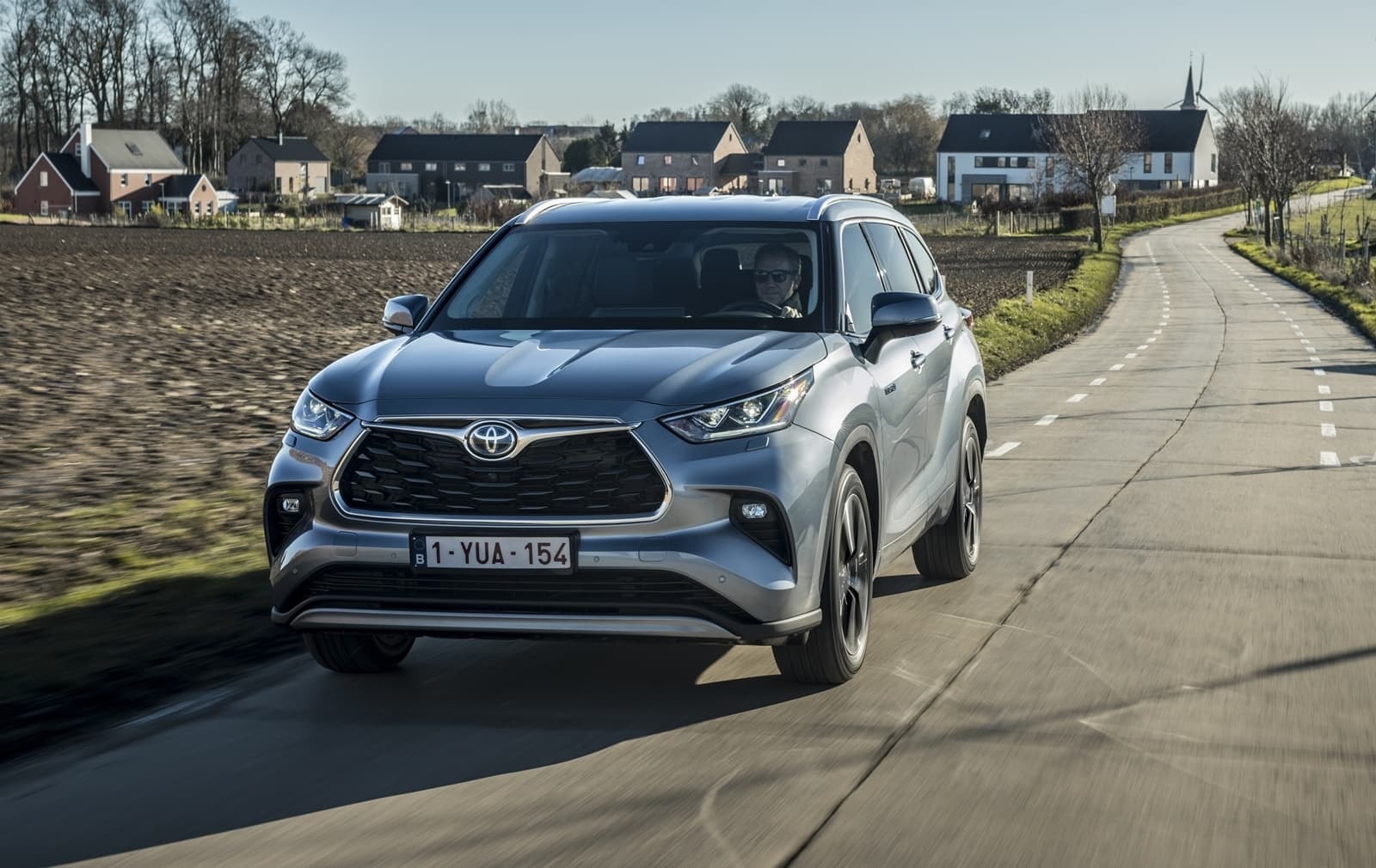 Perfil del Toyota Highlander Híbrido en una carretera con luz natural.