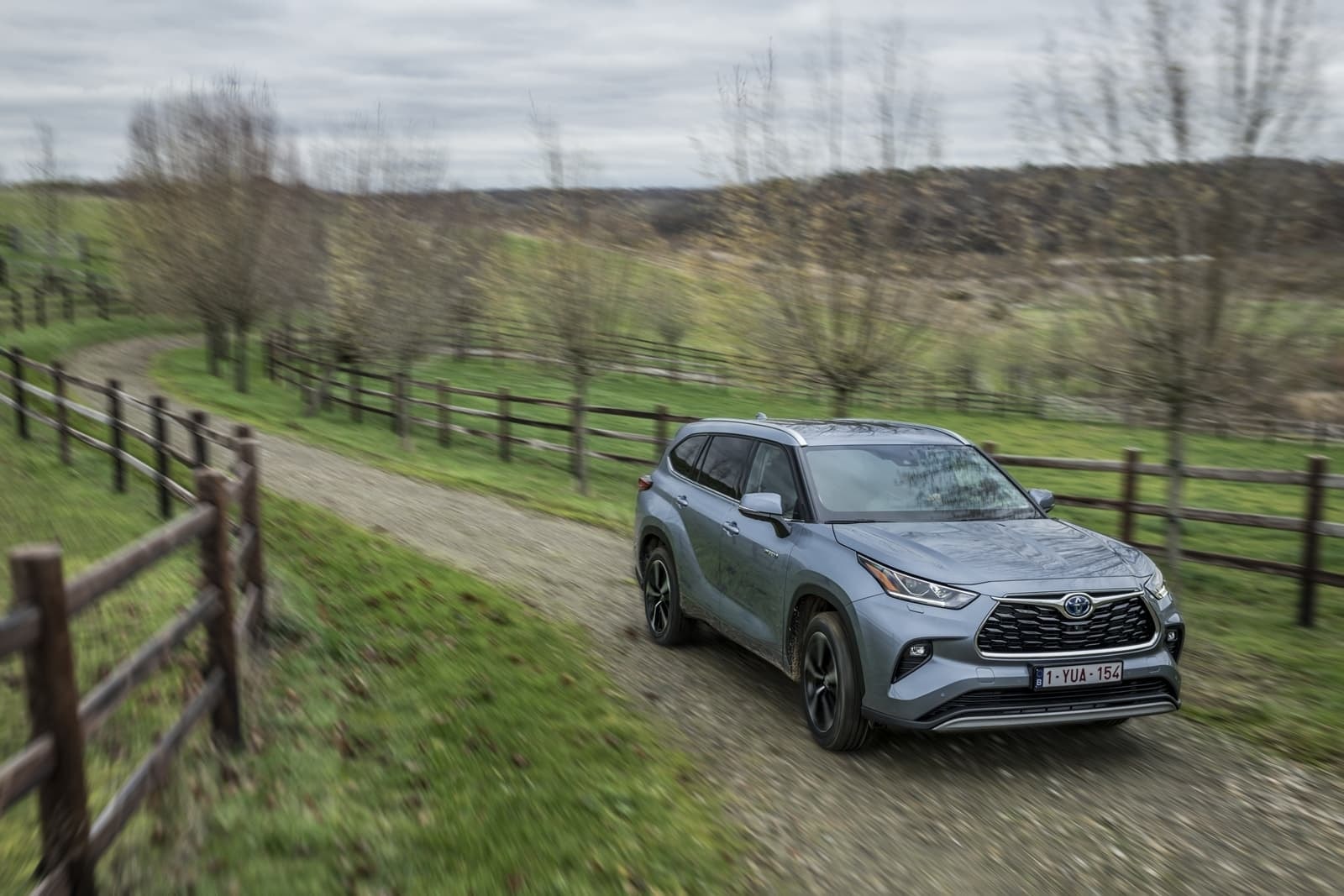 Lado del Highlander Híbrido navegando por un entorno campestre.