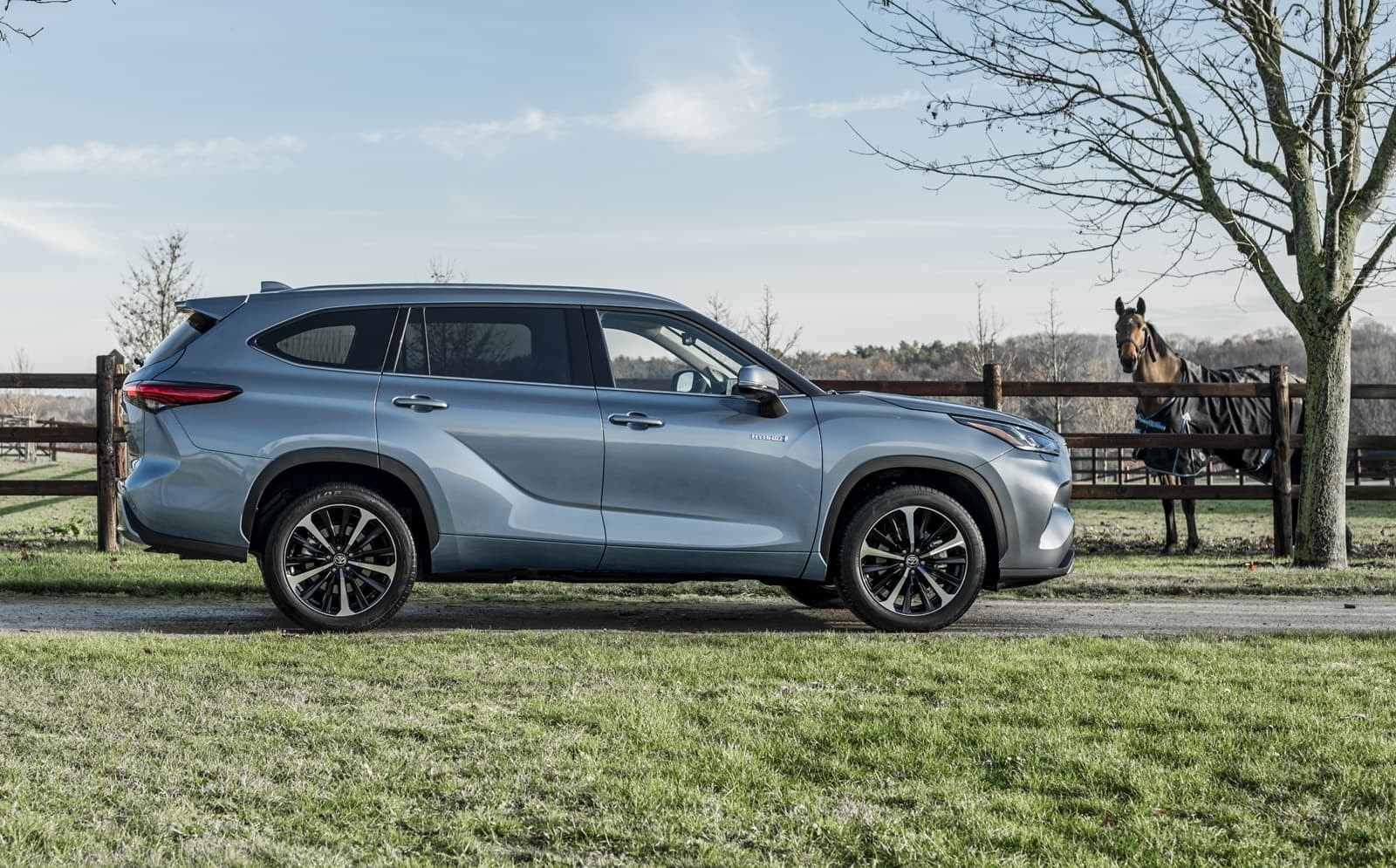 Vista lateral del Toyota Highlander en un ambiente rústico.