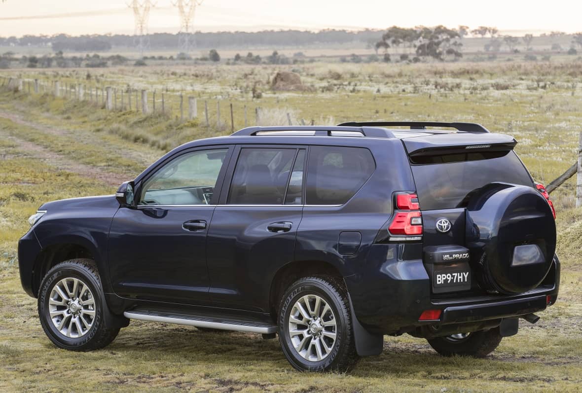 Rear and side view of a Toyota Land Cruiser in a field.