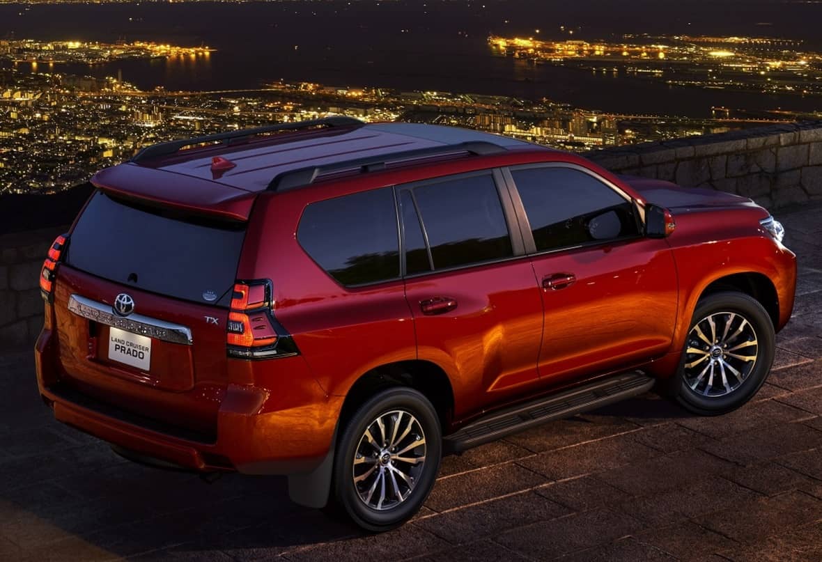 Vista trasera lateral del Land Cruiser con la ciudad nocturna como telón de fondo.