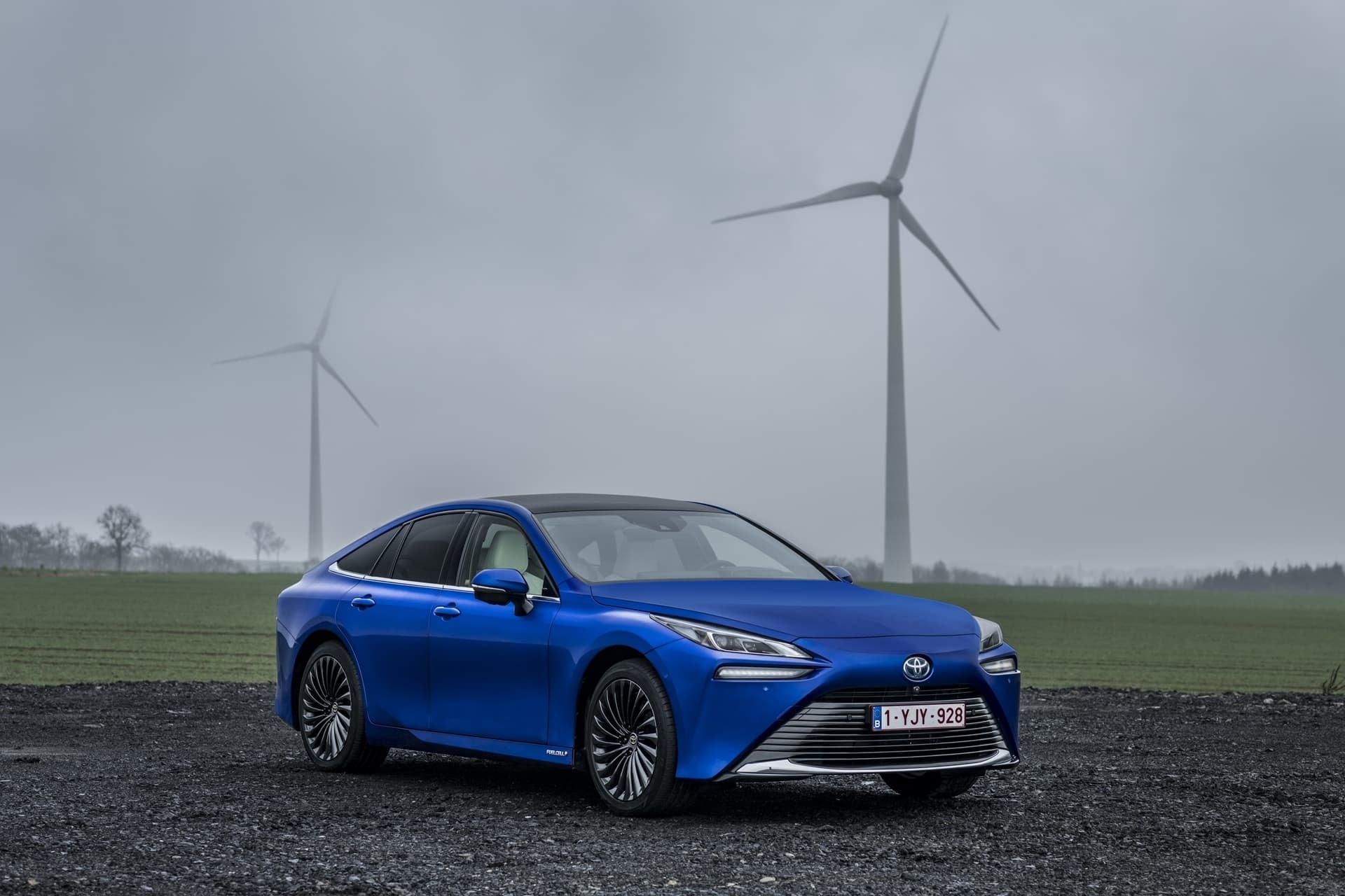 Perfil del Toyota Mirai con molinos de viento, enfatizando sostenibilidad.