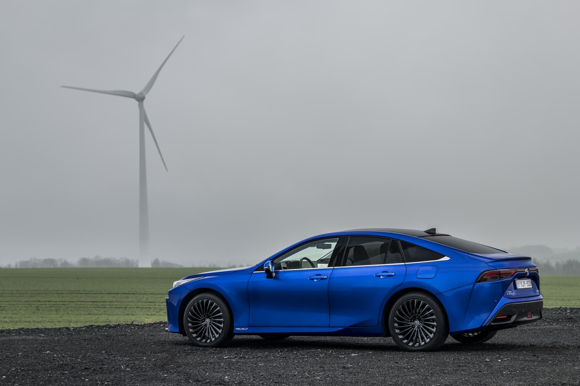 Perfil lateral del Toyota Mirai con turbinas eólicas, simbolizando su sostenibilidad.