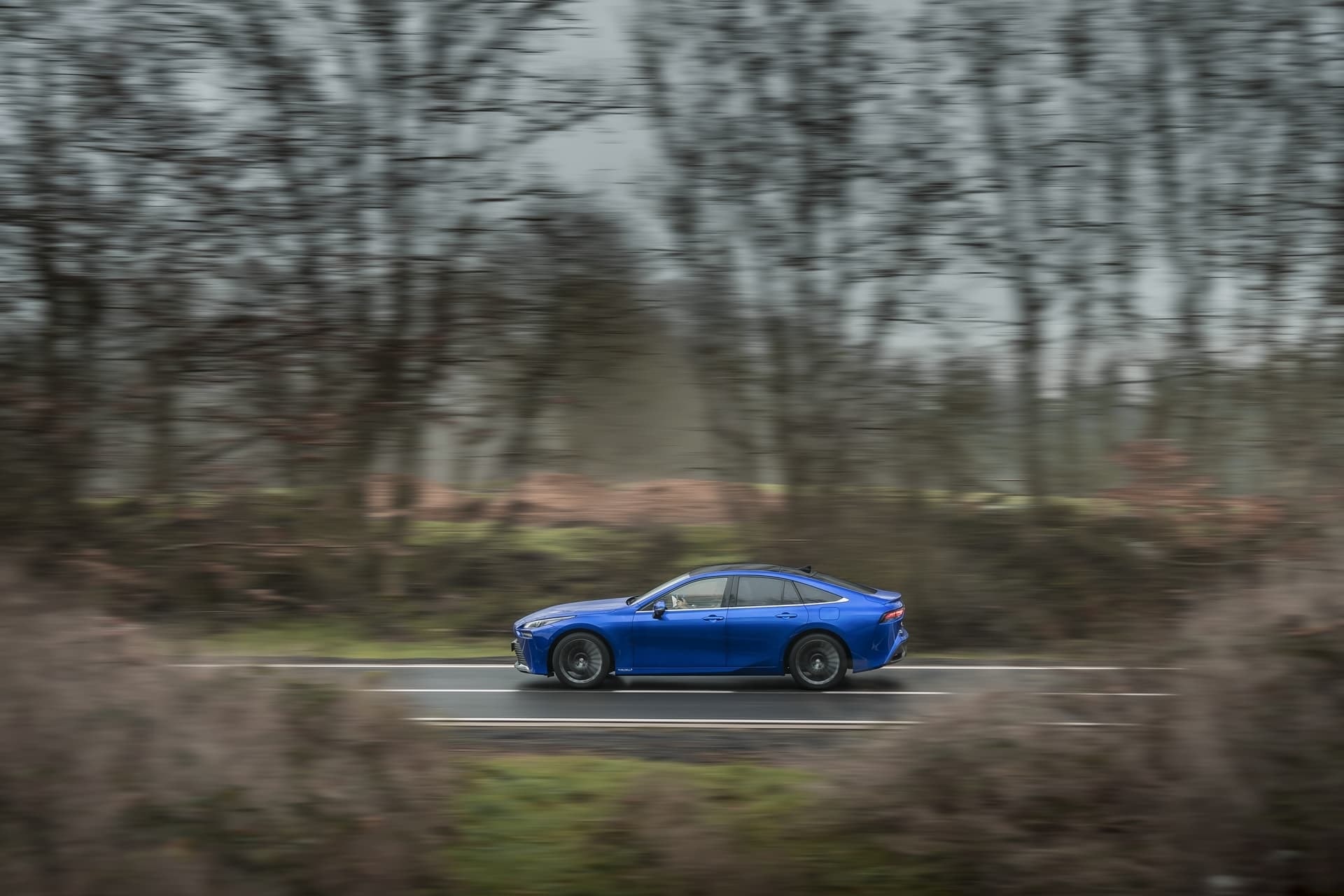 Lateral y parte trasera del Mirai azul en movimiento, enfatizando su diseño deportivo.