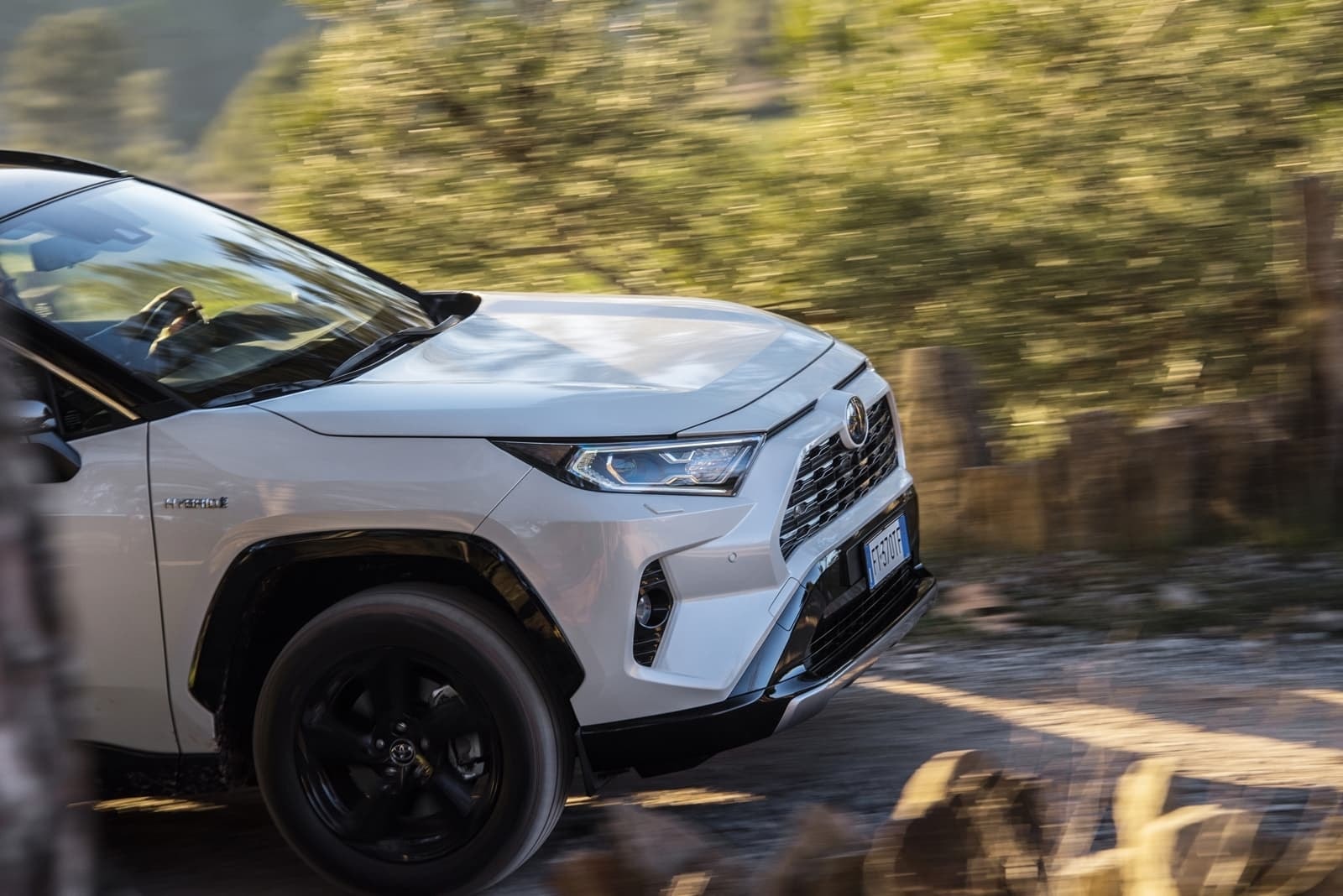 Detalle de la parte lateral del RAV4 híbrido, mostrando líneas de diseño y ruedas.