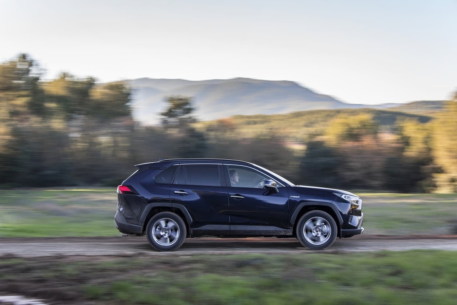 Perfil lateral en movimiento del Toyota RAV4 Híbrido, destacando su línea aerodinámica.