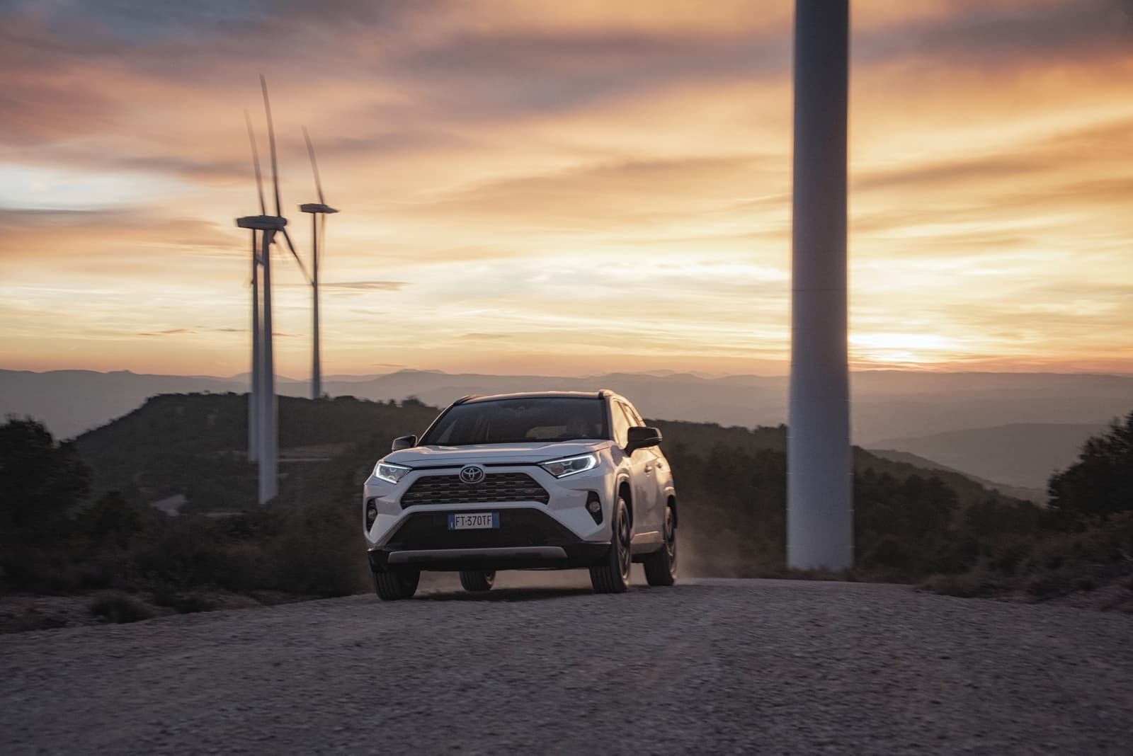 El RAV4 híbrido capturado de frente en una escena de atardecer, proporcionando una imagen aventurera.