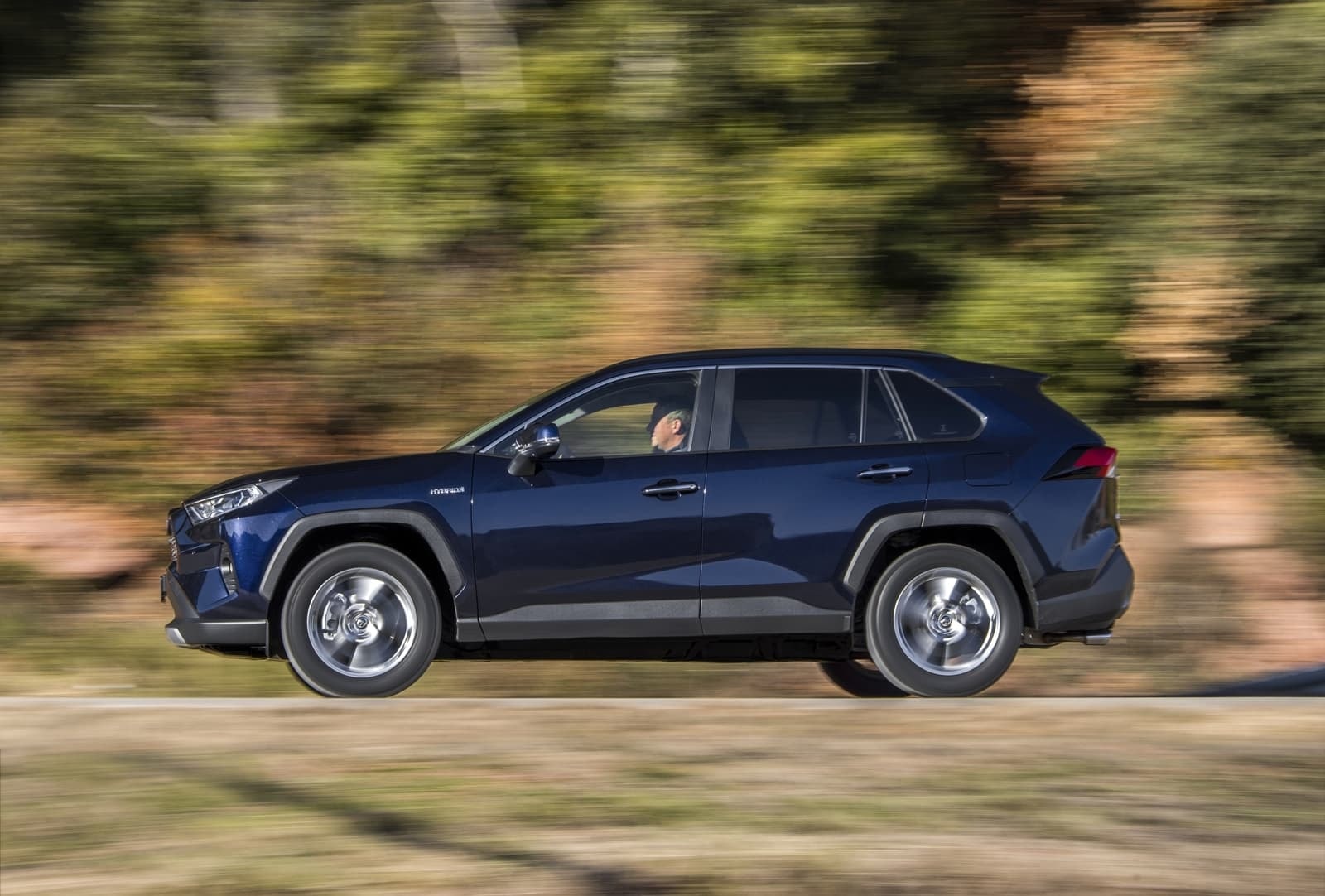 Lateral del RAV4 Híbrido captado en pleno movimiento, mostrando su diseño elegante.