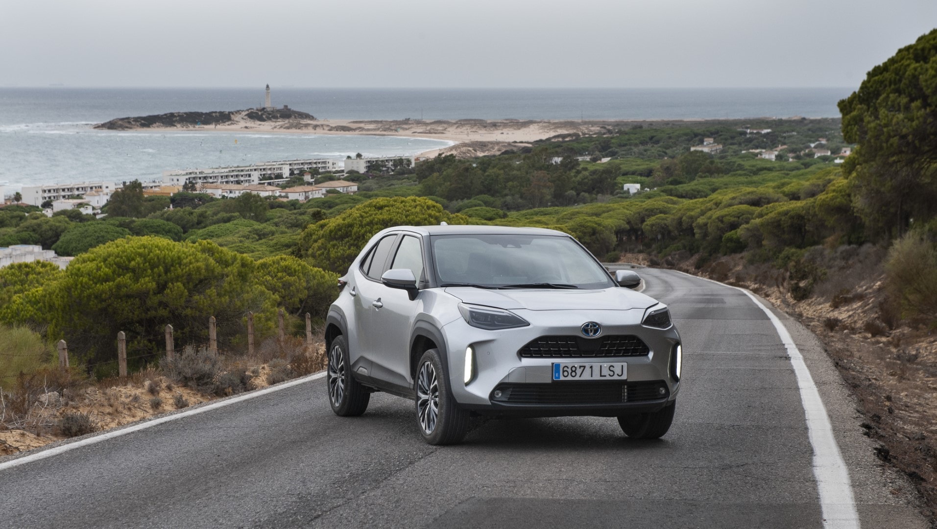 Vista frontal y lateral del Toyota Yaris Cross híbrido en un entorno natural, ideal para viajes.