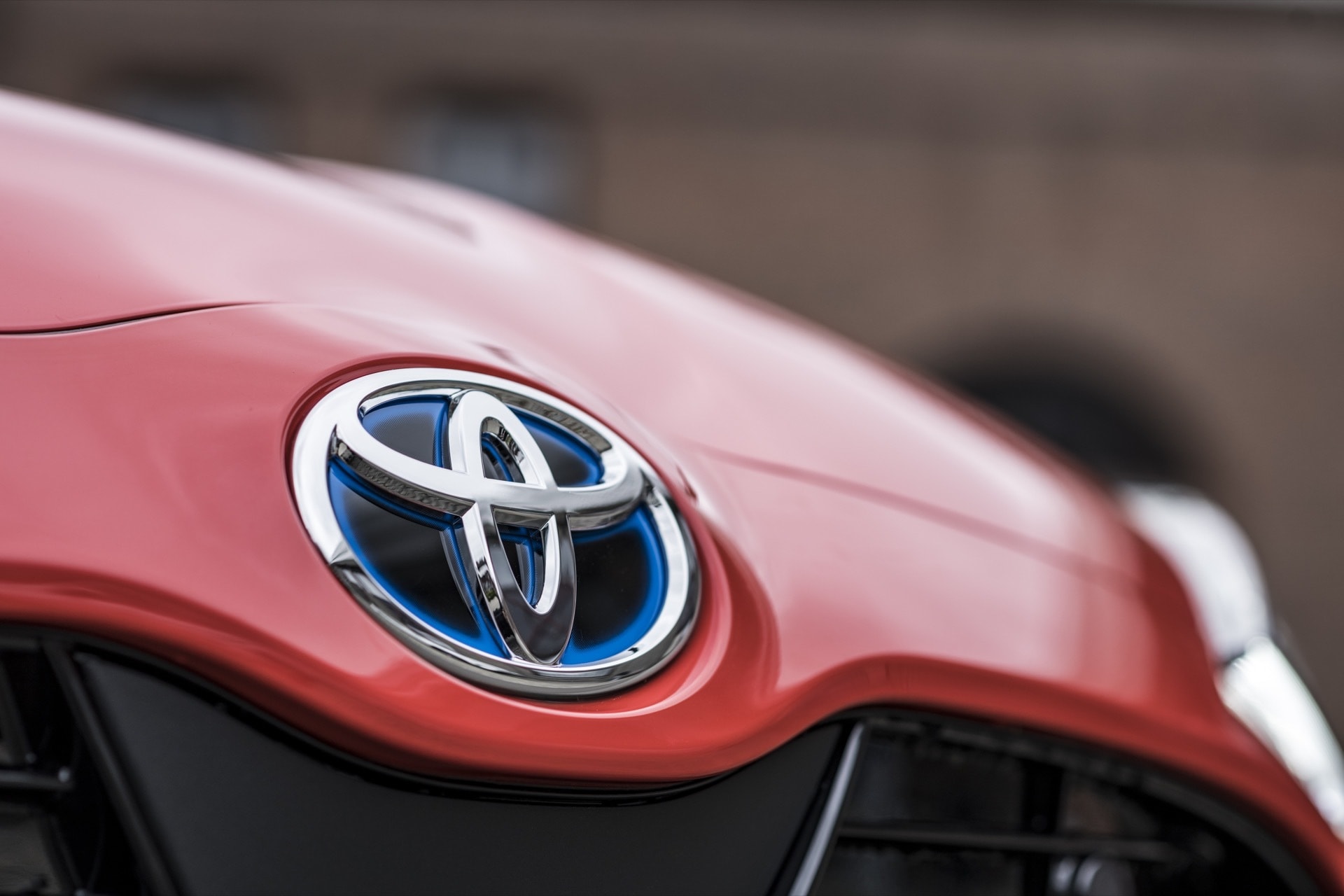 Primer plano del logo de Toyota en el Yaris, con detalles azules de la versión híbrida.
