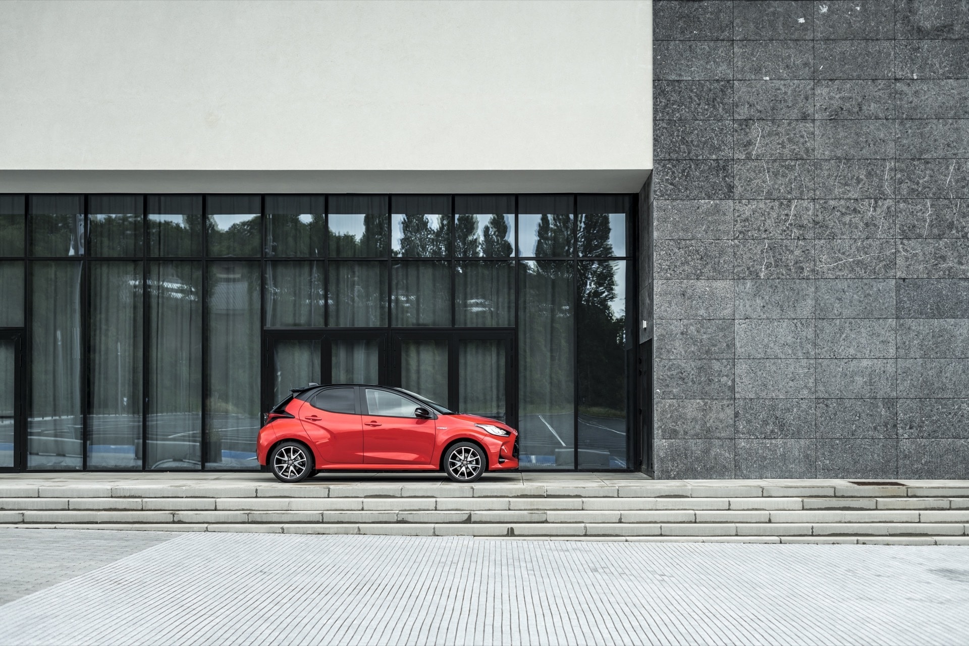 Toyota Yaris lateral trasero con un fondo de arquitectura moderna, realzando su presencia