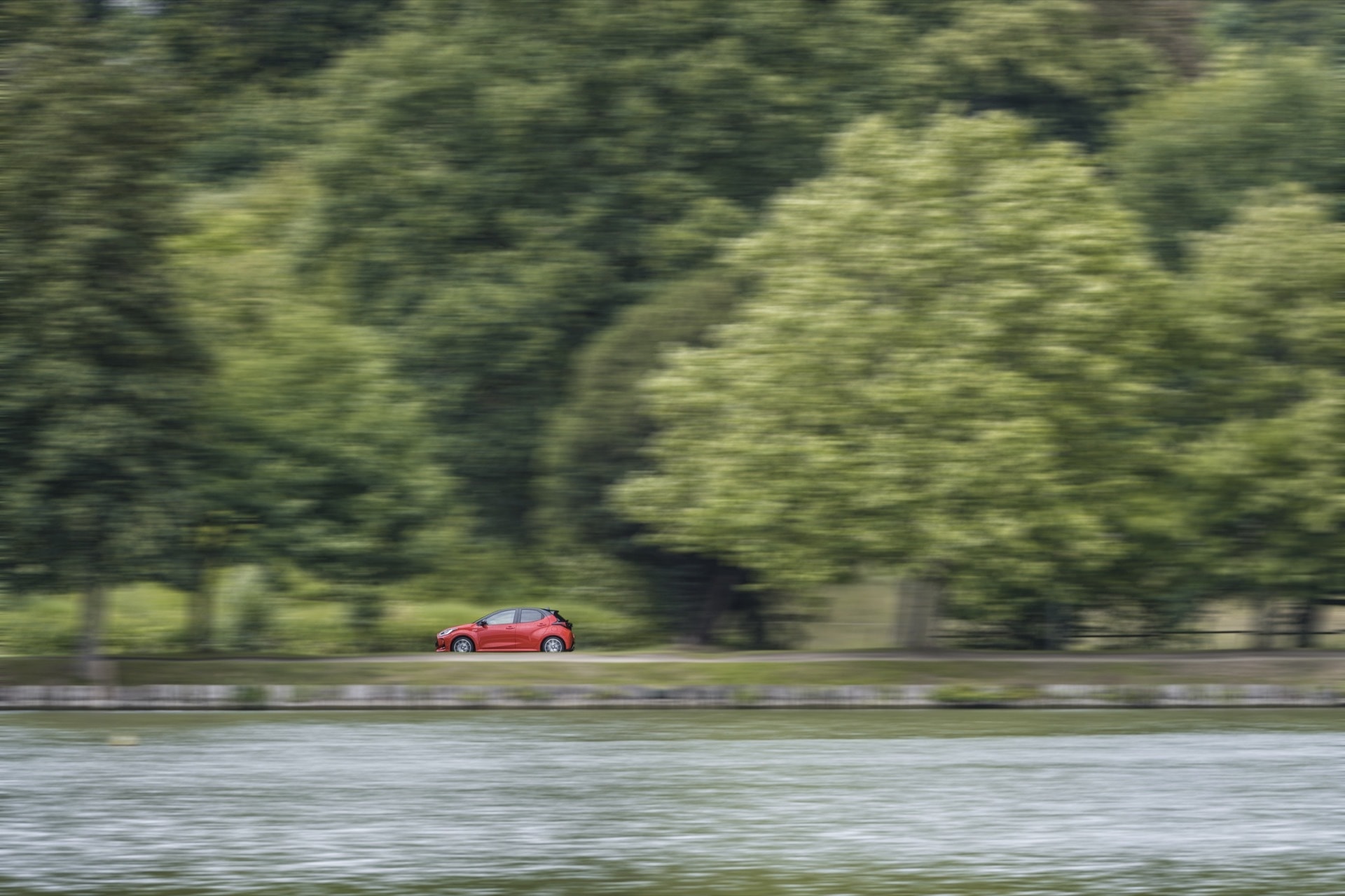 Toyota Yaris lateral en velocidad, integrado en un entorno natural.