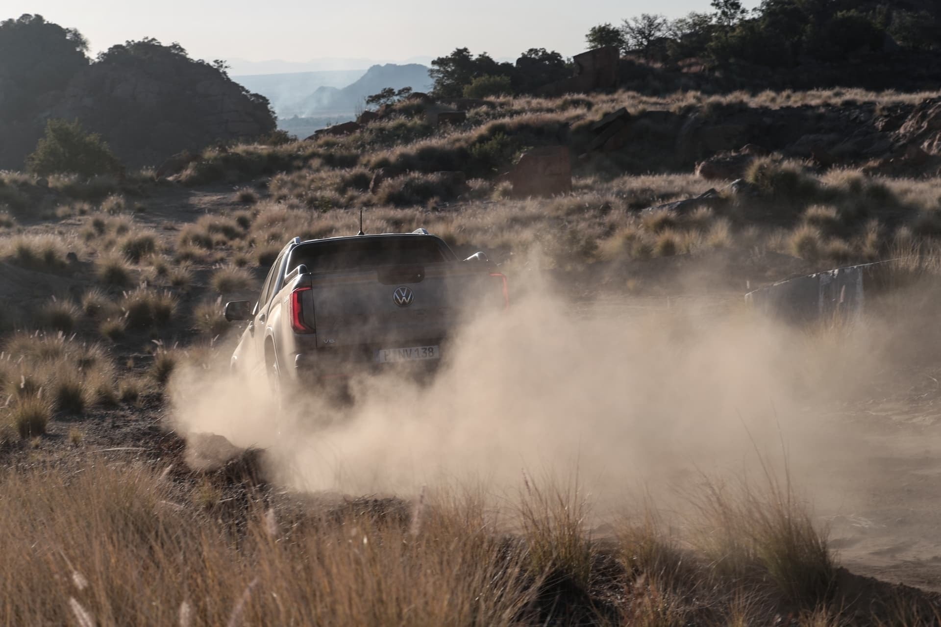 Rear view of the Volkswagen Amarok kicking up dust.