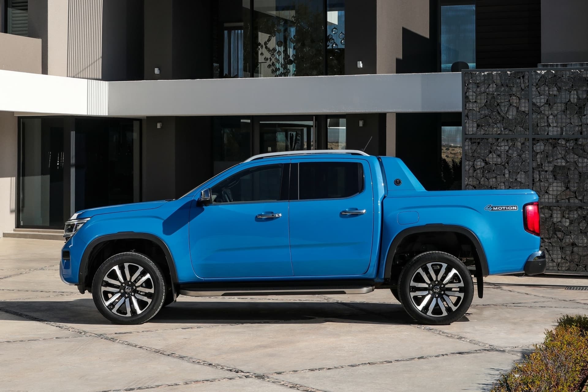 Perfil lateral del Amarok estacionado frente a un edificio moderno.