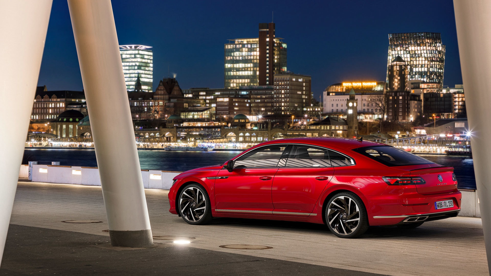 Arteon mostrando su porte nocturno con paisaje urbano de fondo.