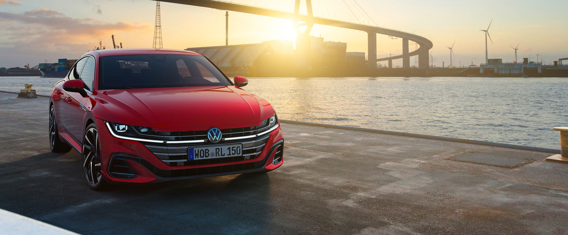 Arteon rojo frente al puerto al atardecer, vista delantera.