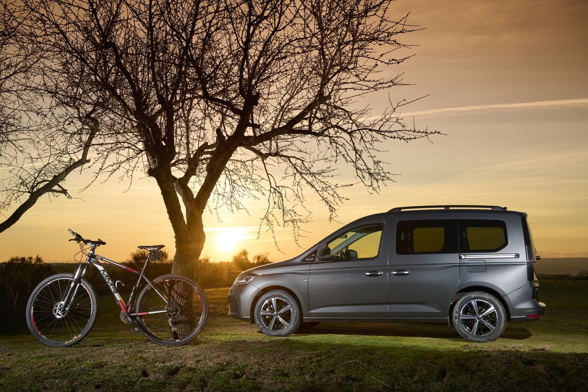 Perfil lateral del Caddy con una bicicleta en primer plano y el sol bajando.