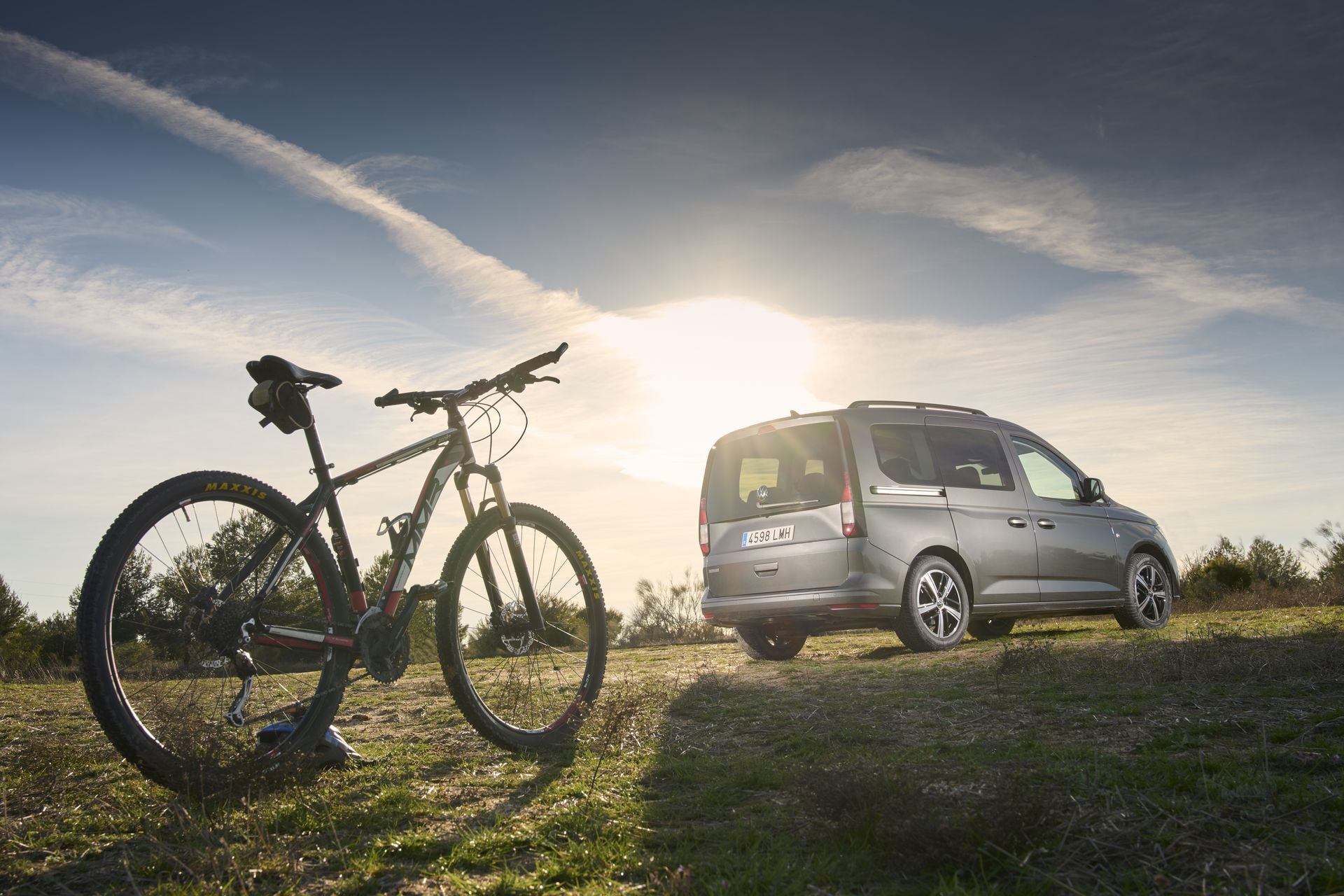 Volkswagen Caddy junto a una bicicleta en paisaje al atardecer.