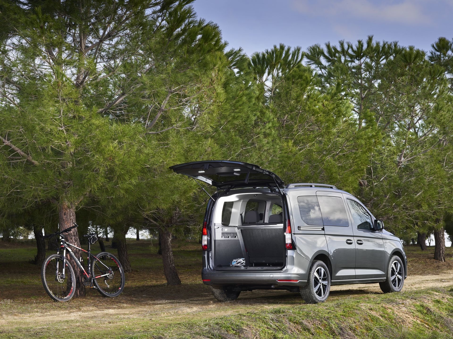 Volkswagen Caddy estacionado en el campo, con la puerta trasera abierta.