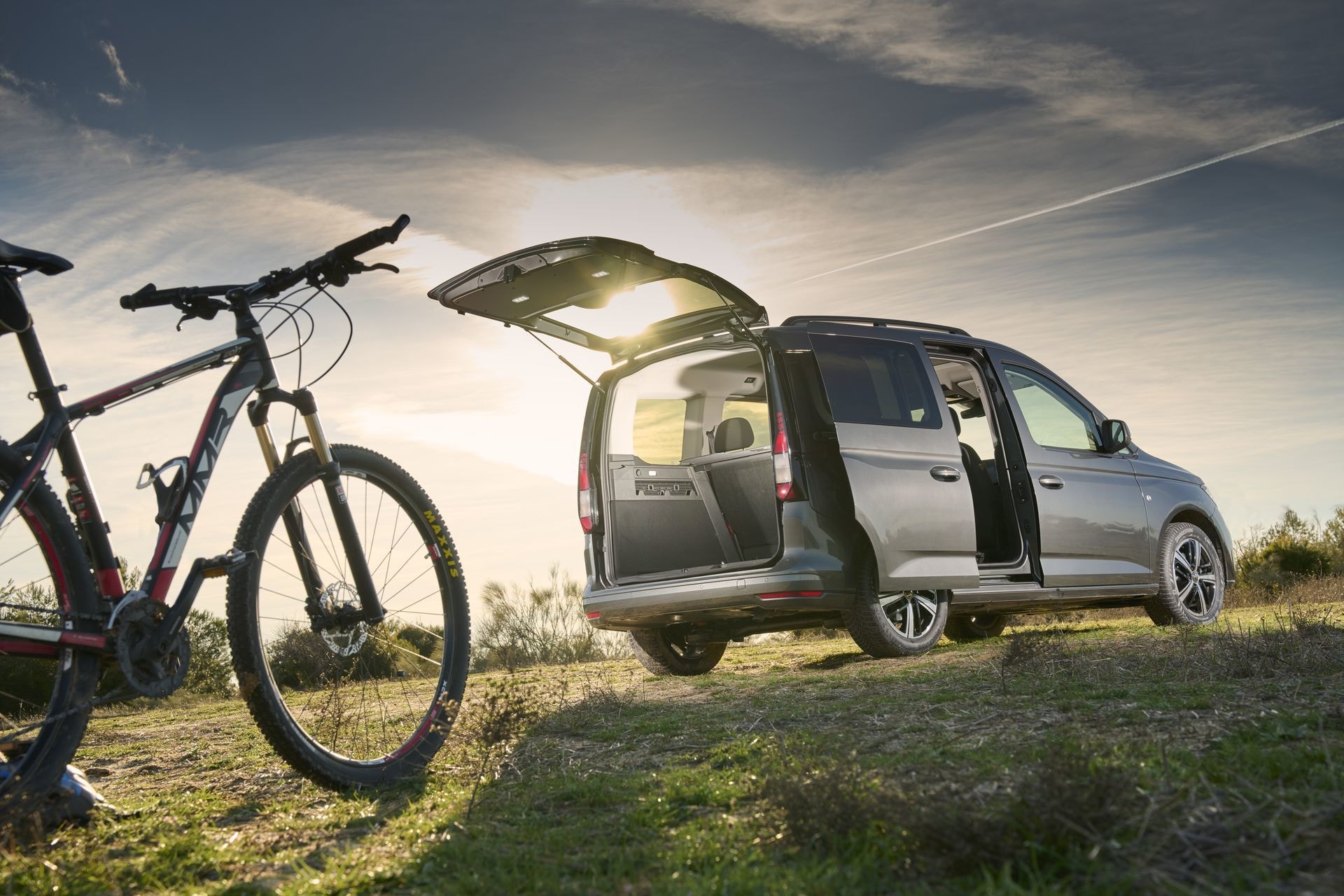 Volkswagen Caddy con el maletero abierto y bicicleta al lado.