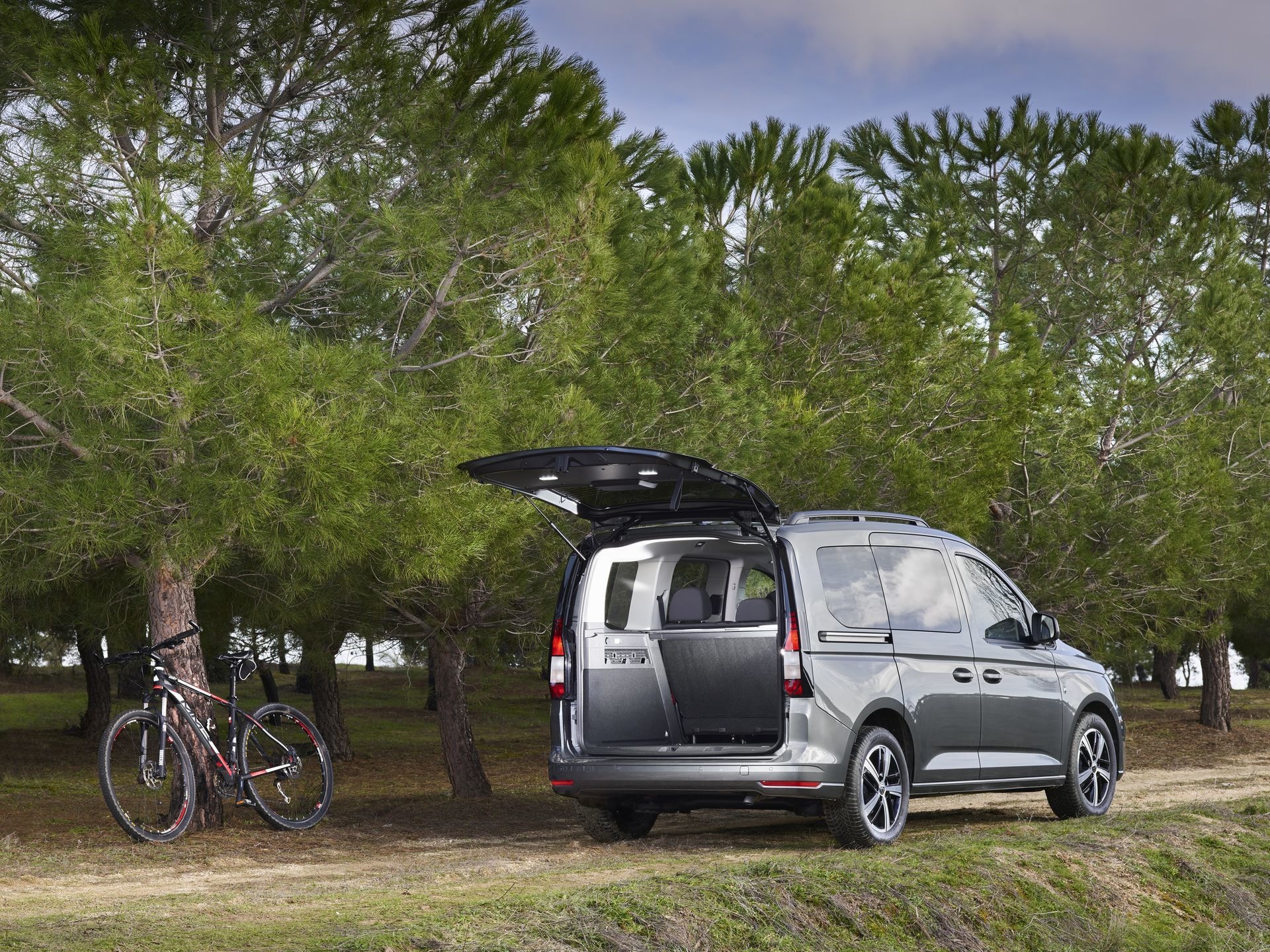 Volkswagen Caddy con maletero abierto listo para cargar bicicletas en la naturaleza.