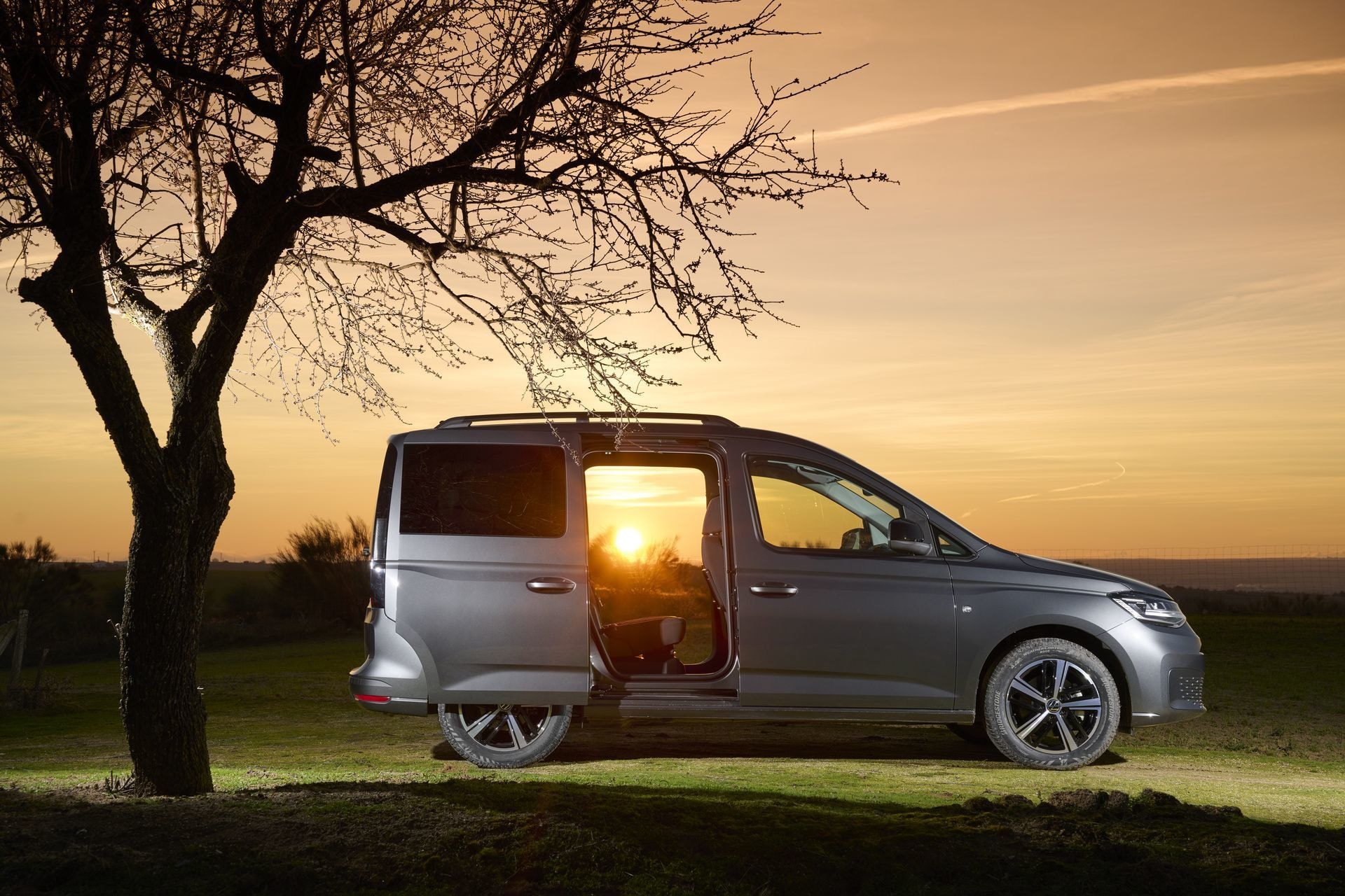 Volkswagen Caddy con maletero abierto y equipo de ciclismo al atardecer.