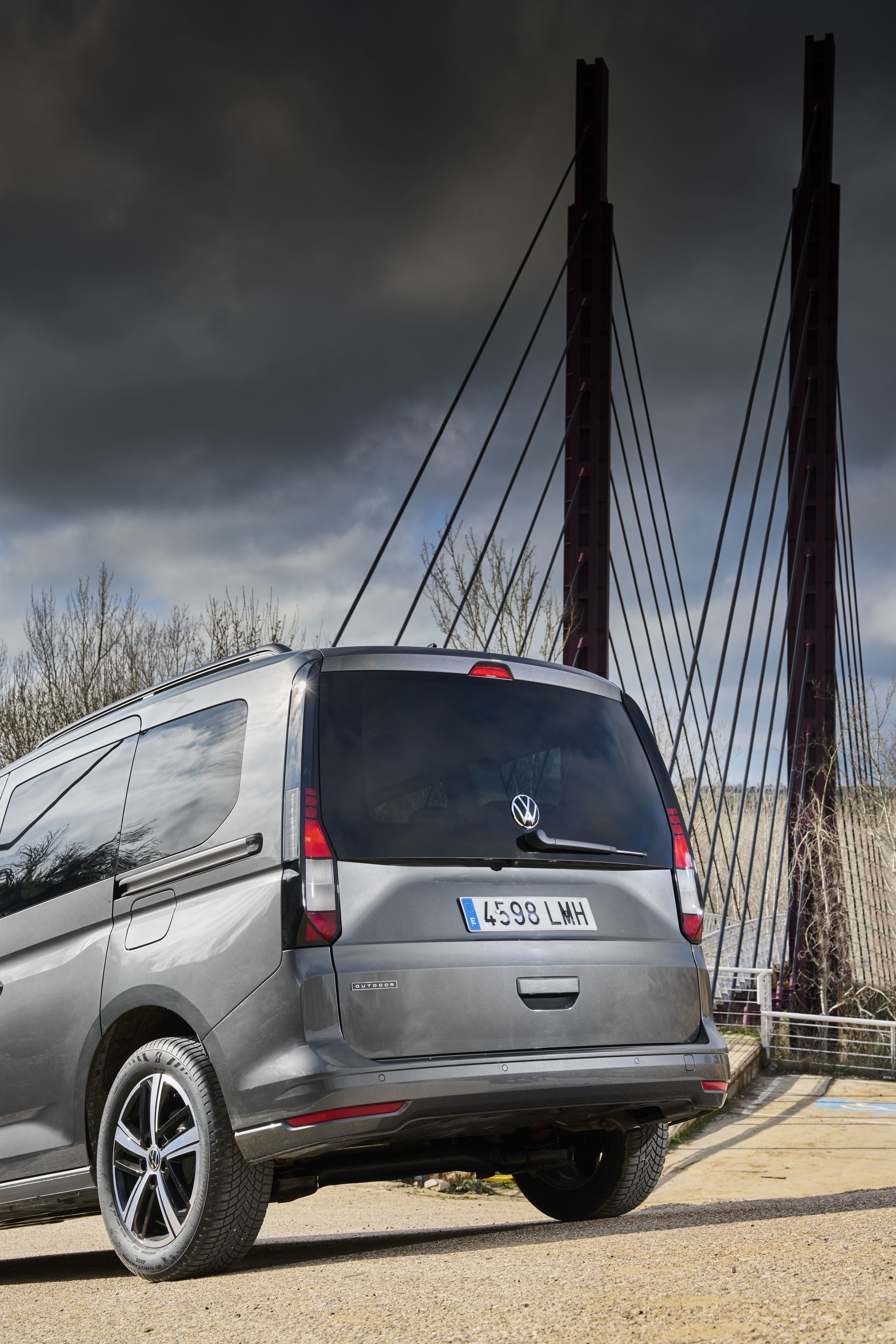 Vista trasera y lateral del Volkswagen Caddy con un puente de fondo.