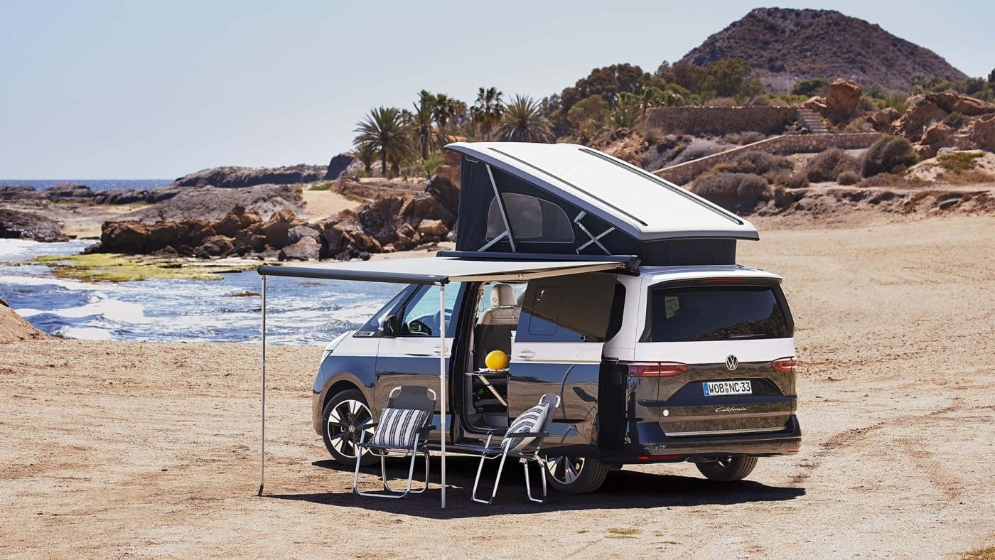 Contexto de uso de una Volkswagen California en ambiente de playa con accesorios de camping.