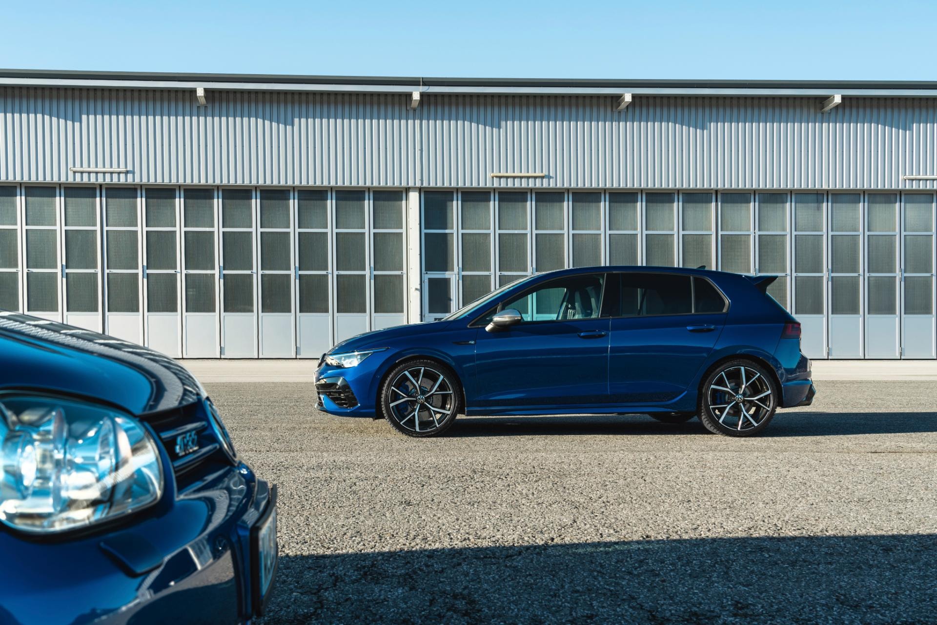 Perfil lateral del Volkswagen Golf R con un fondo de arquitectura contemporánea, destacando su diseño.