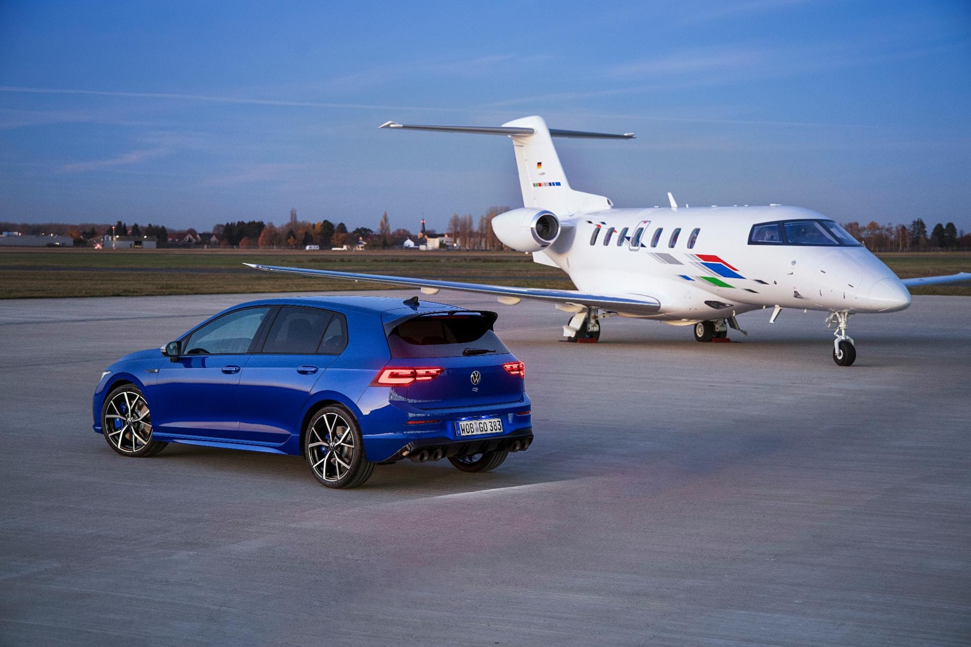 Trasera del Golf R en pista de aeropuerto con un jet privado en el fondo.