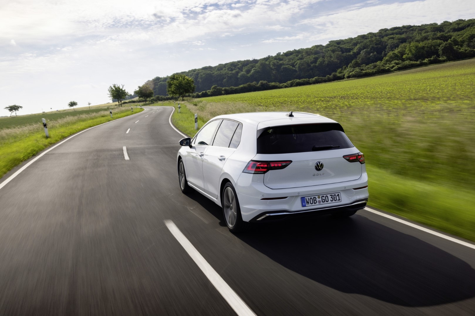 Vista trasera del Volkswagen Golf en una carretera verde. Diseño moderno y aerodinámico.