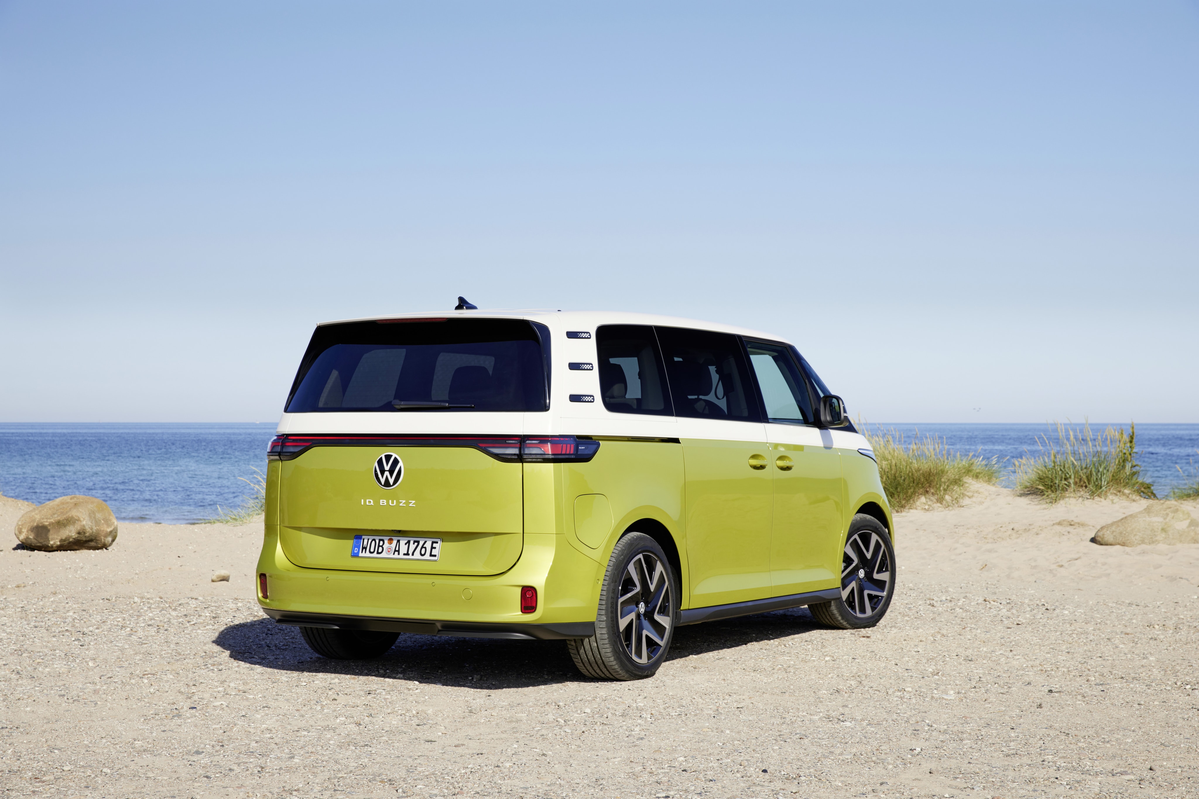 Perfil trasero del Volkswagen ID. Buzz frente a un paisaje costero sereno
