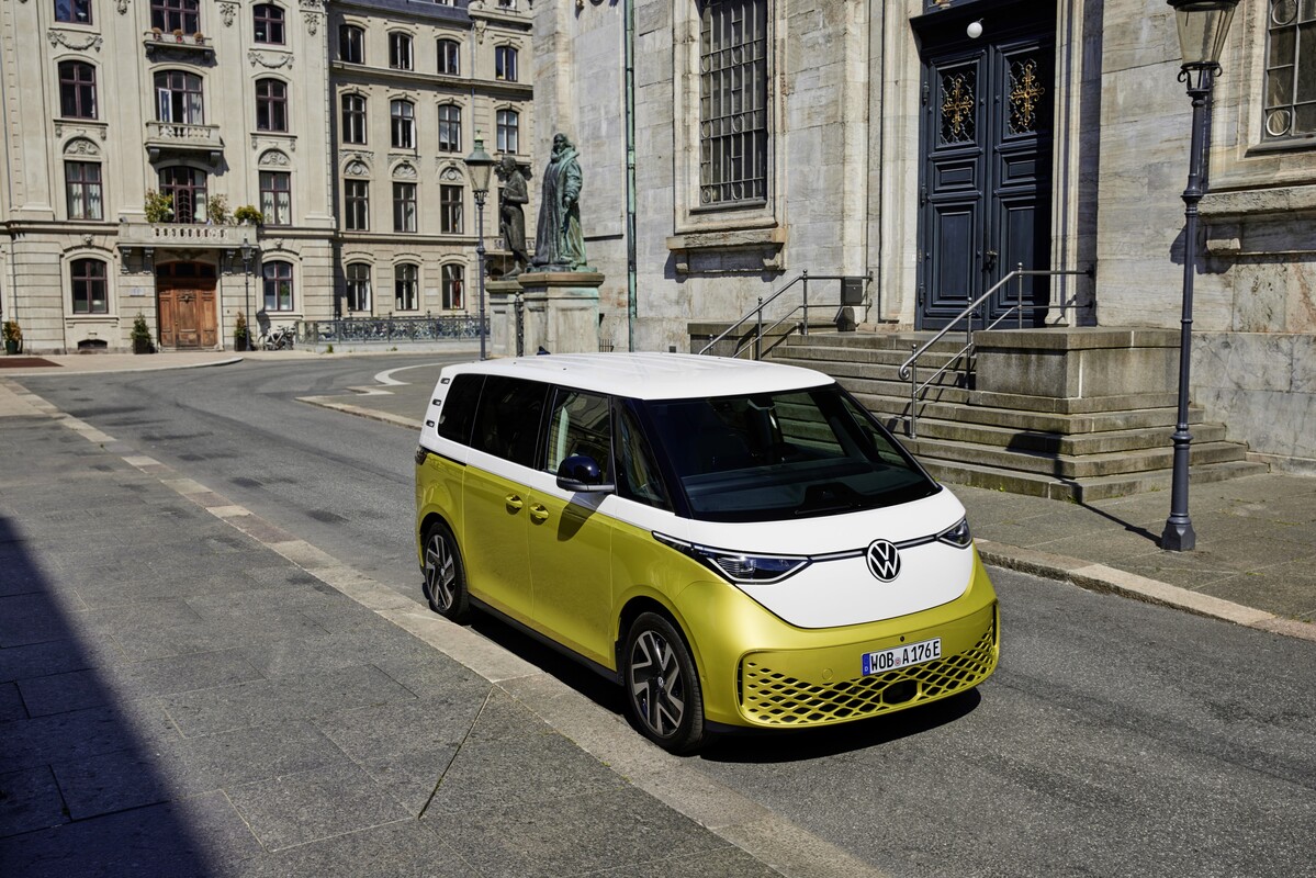 Volkswagen ID. Buzz delante de una fachada histórica, fusión de épocas Volkswagen ID. Buzz delante de una fachada histórica, fusión de épocas