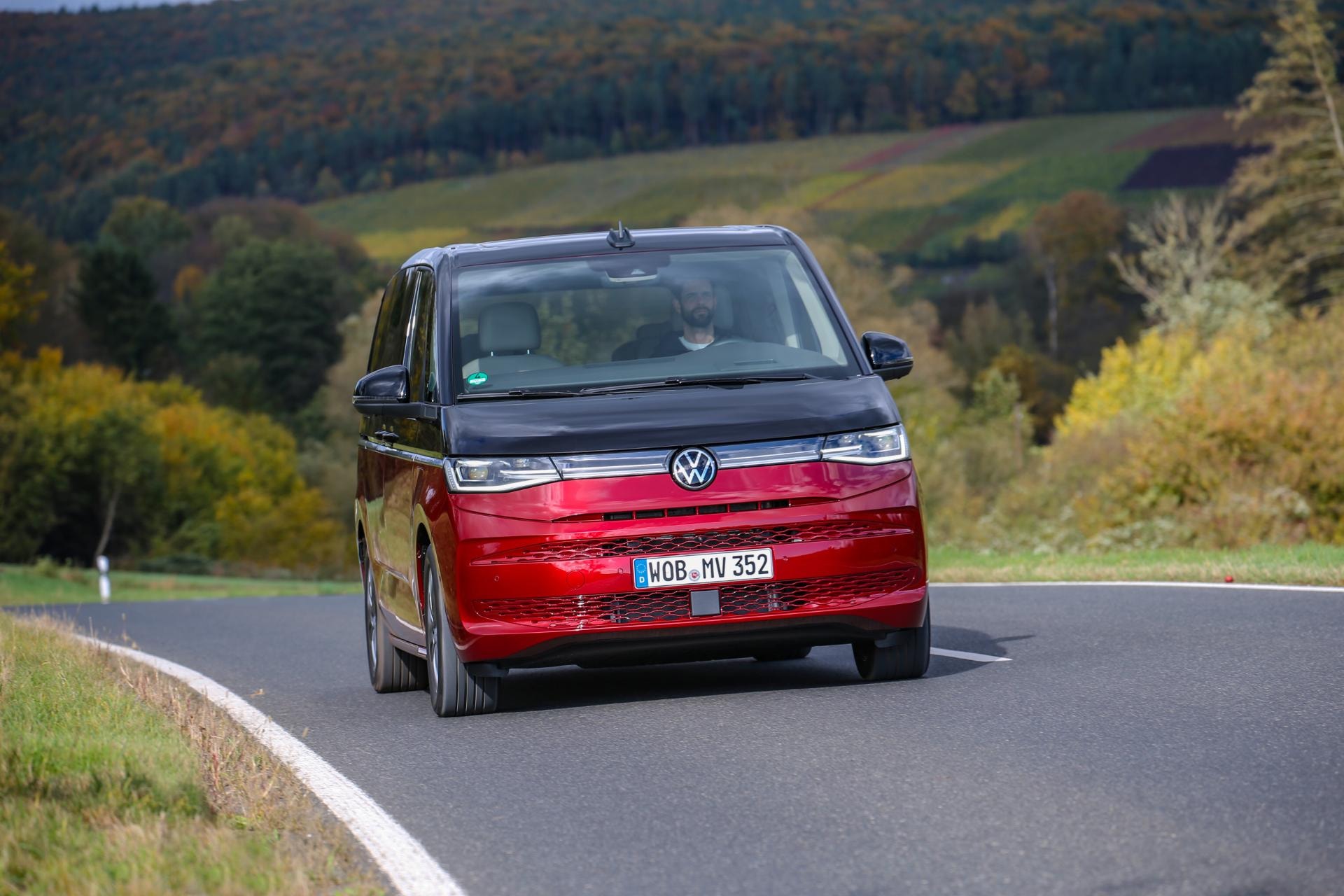 Vista delantera del Volkswagen Multivan híbrido, enfatizando su diseño mientras circula.